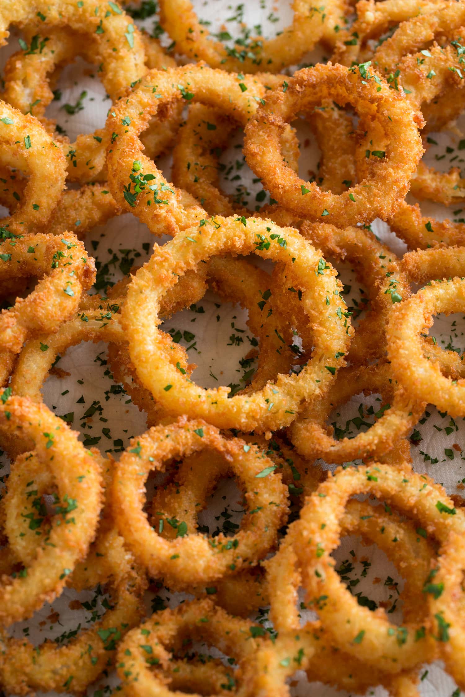 Onion Rings Close up photo of breaded and fried onions layered over each other and garnished with parsley.