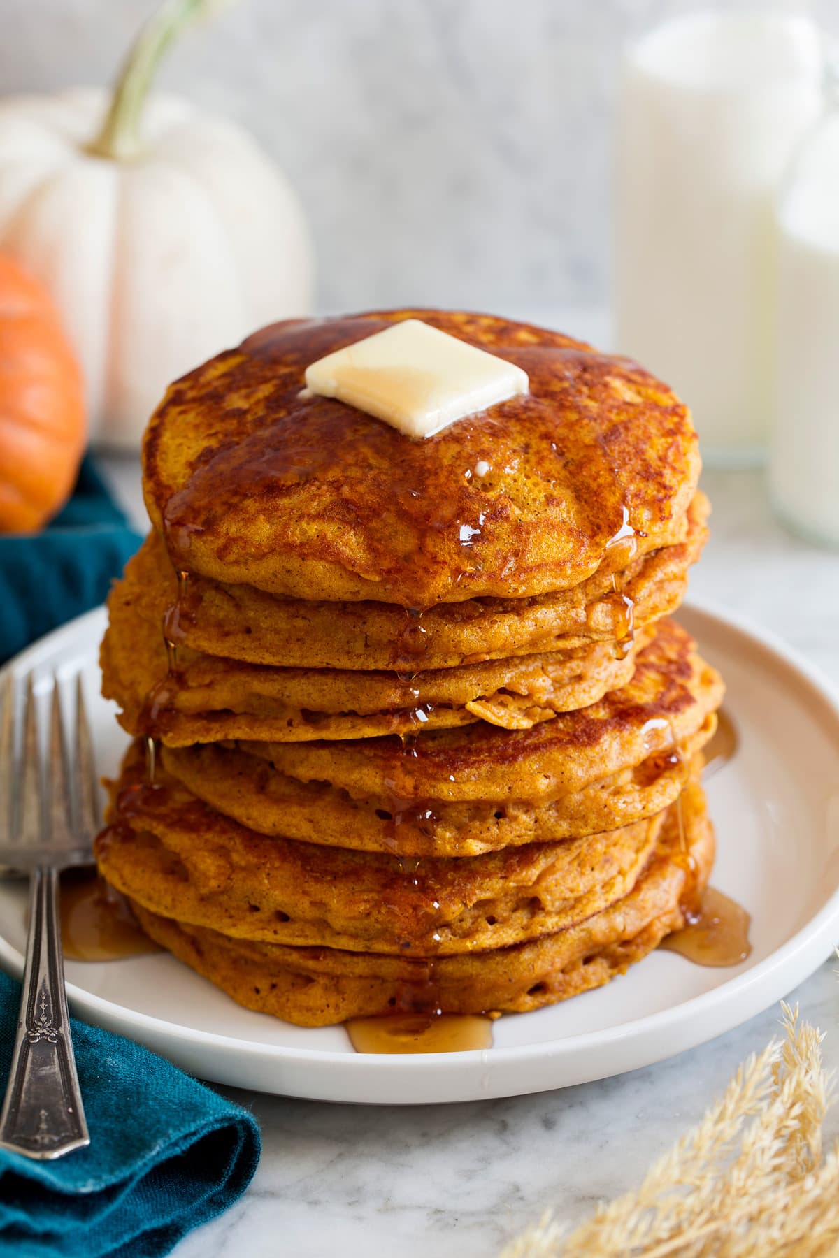 Pumpkin Pancakes Stack of pumpkin pancakes on a platter. Pancakes are drizzled with maple syrup and topped with butter.