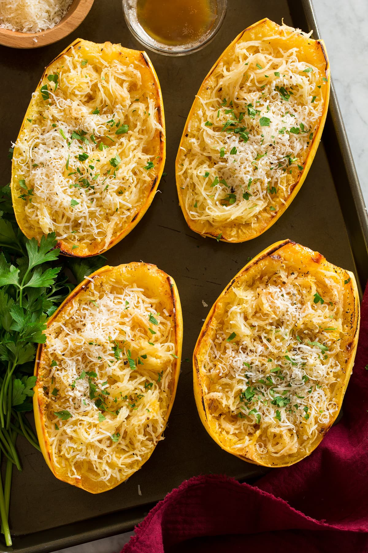 Roasted Spaghetti Squash with Browned Butter and Parmesan Overhead image of four roasted spaghetti squashes on a dark baking sheet.