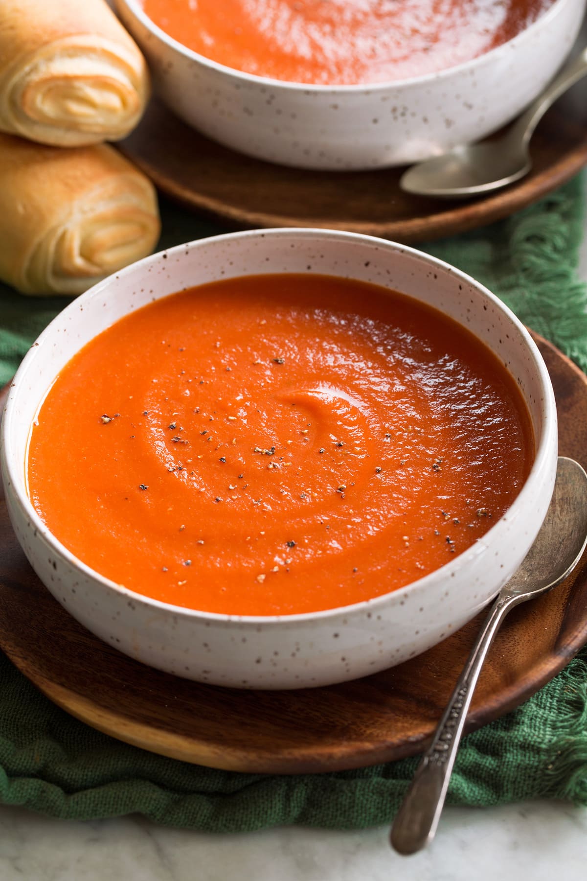 Homemade Tomato Soup Single serving of tomato soup shown in a white bowl set over a wooden plate.