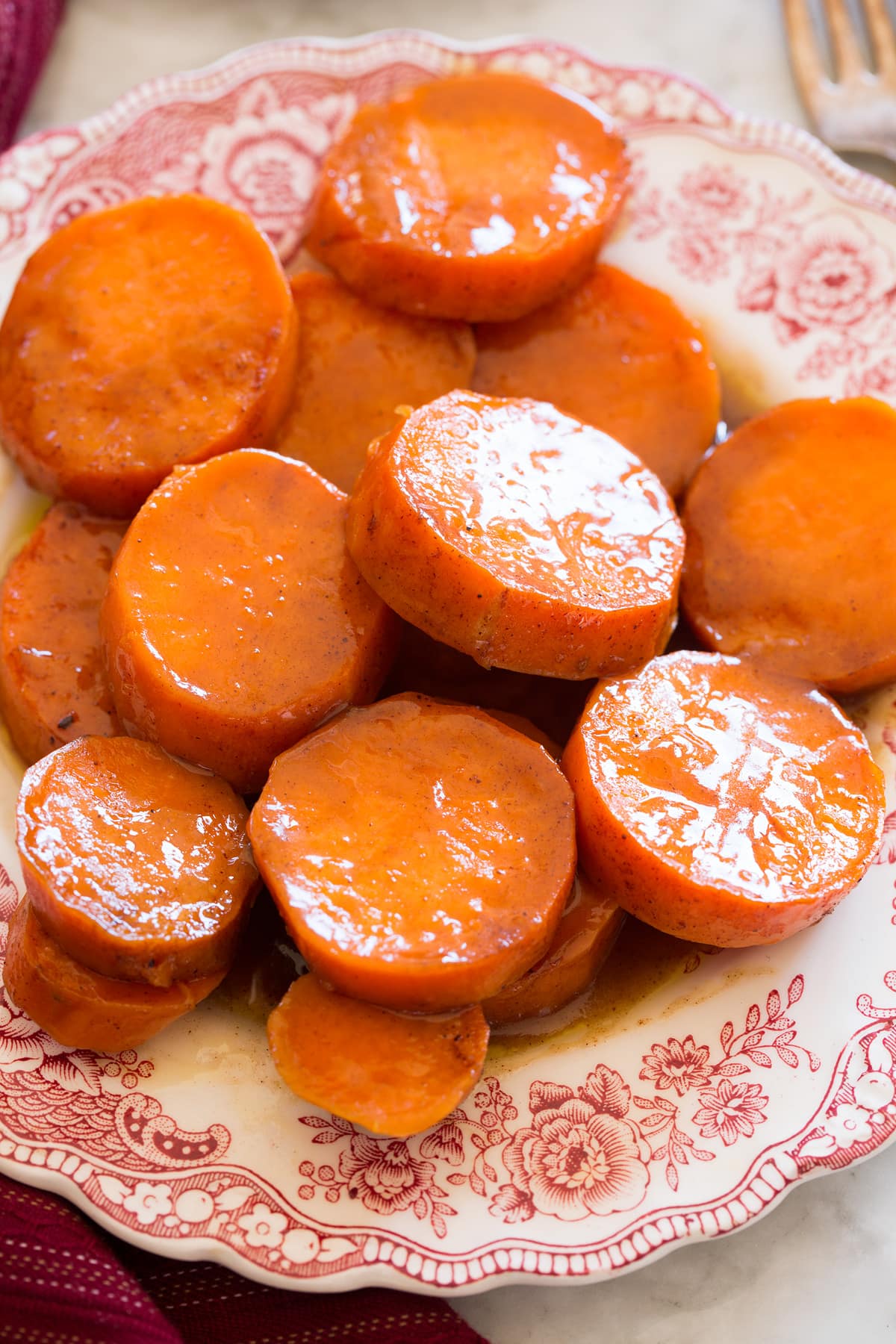Close up image of candied yams on a red and white decorative side plate.
