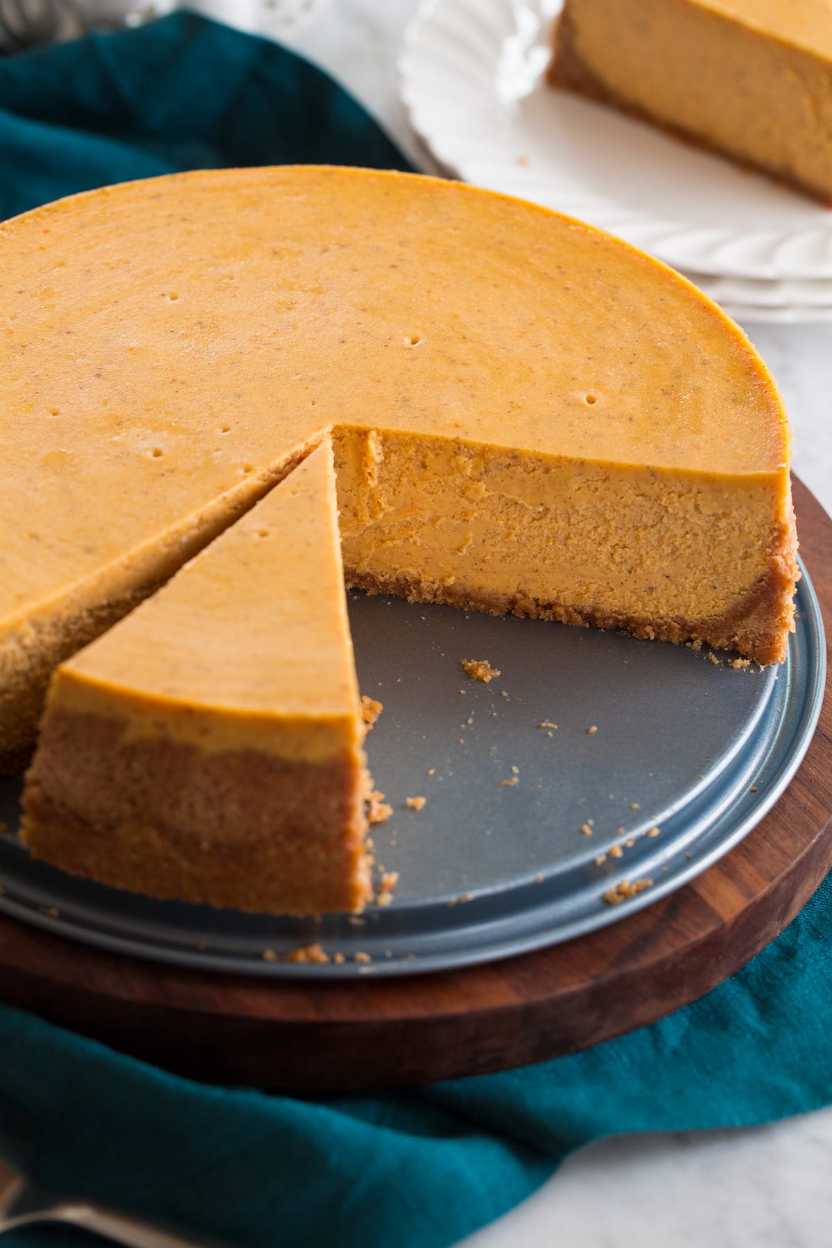 Pumpkin Cheesecake Nearly whole pumpkin cheesecake shown on a platter with a slice cut.