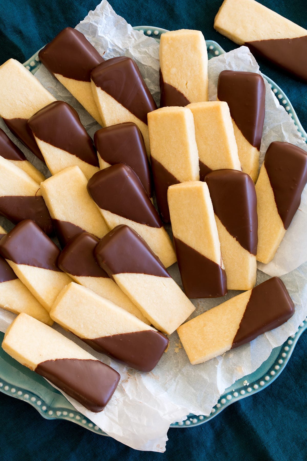 Shortbread Cookies Overhead image of shortbread cookies dipped in chocolate on a blue plate lined with parchment paper.