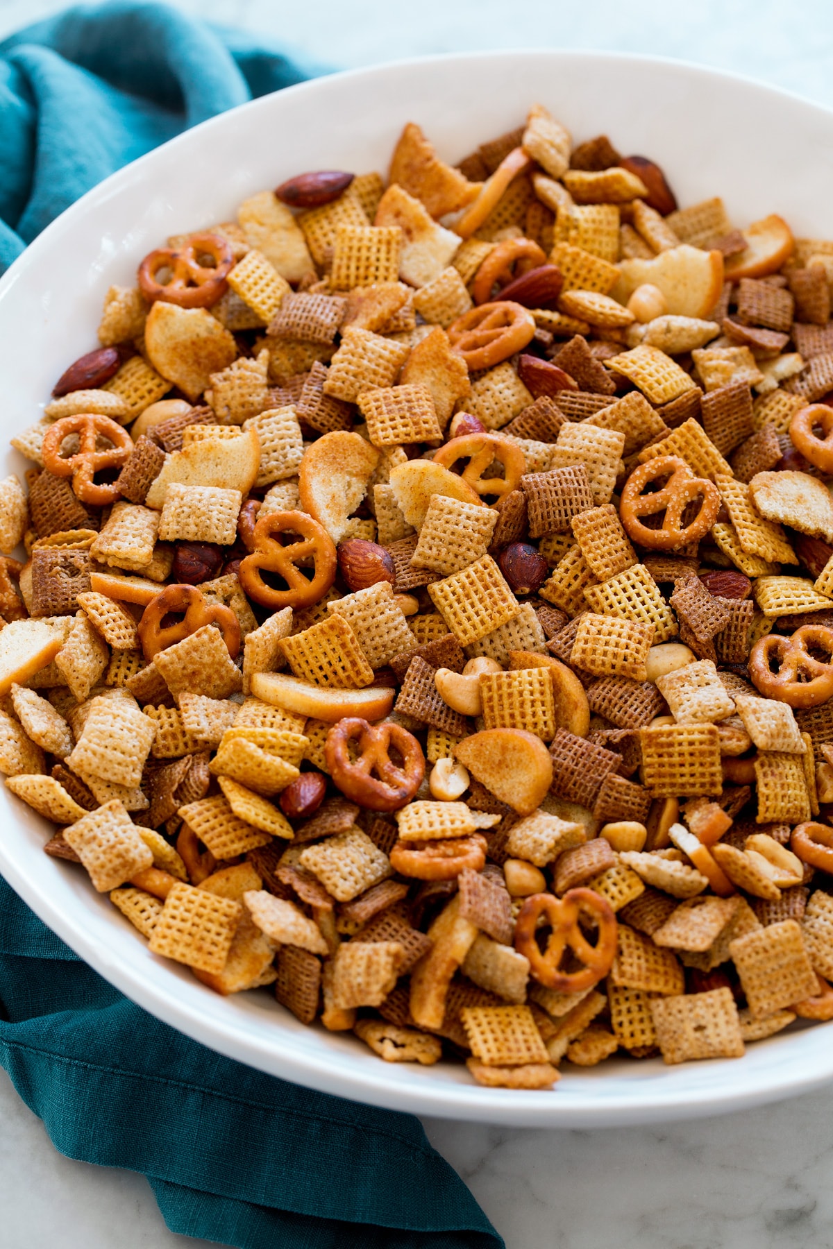 Homemade Chex Mix shown from a side angle in a large white serving bowl.