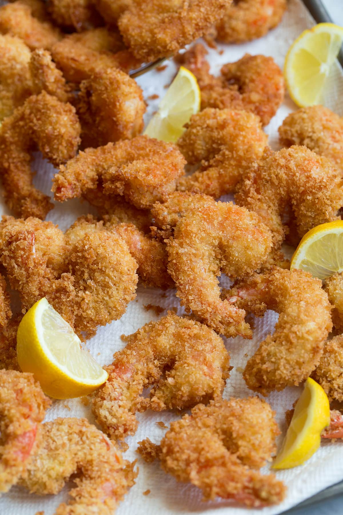 Fried Shrimp Close up photo of panko crusted fried shrimp piled on paper towel lined sheet pan.