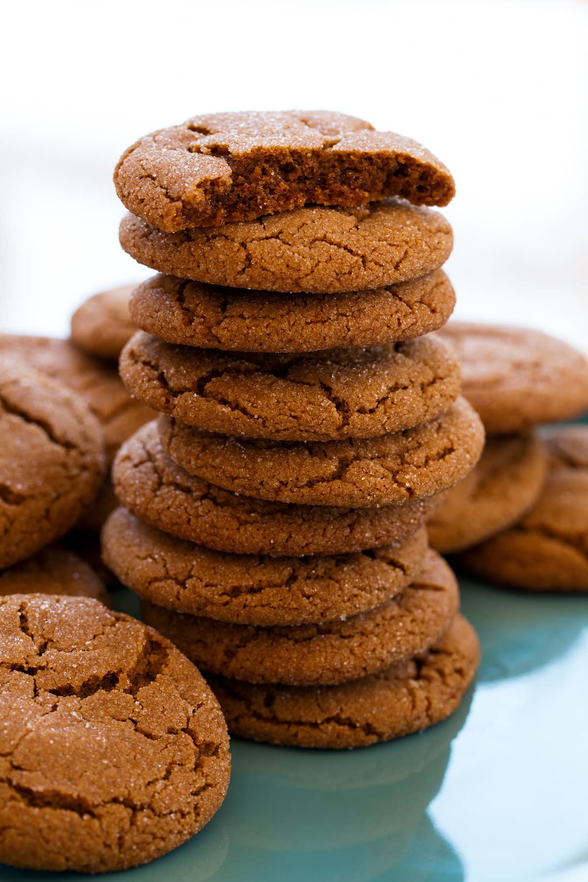 Molasses Cookies Tall stack of molasses cookies with the top cookie broken in half to show soft moist texture of interior.