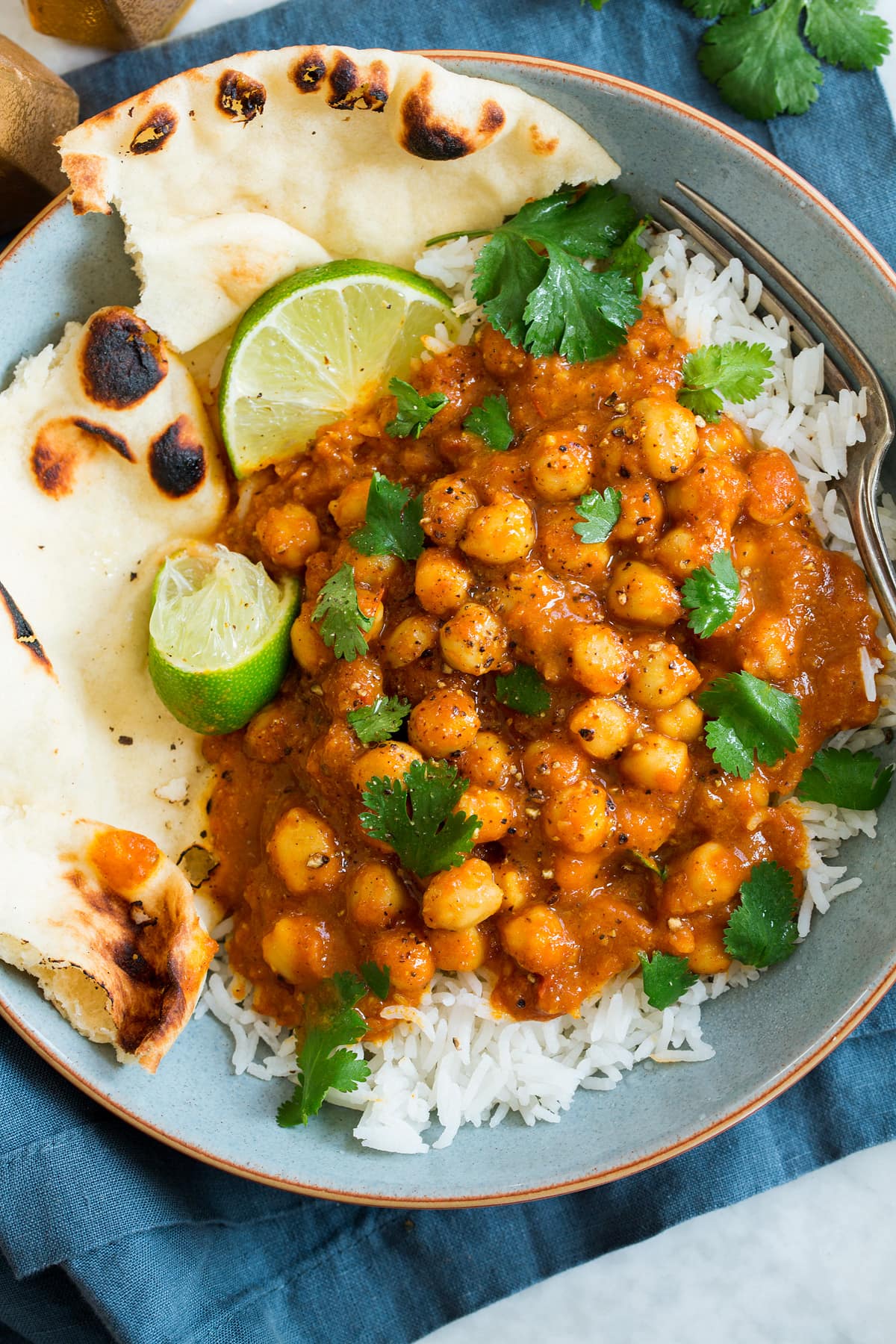 Chickpea Curry Overhead photo of single serving of chickpea curry with rice, naan, cilantro and limes.