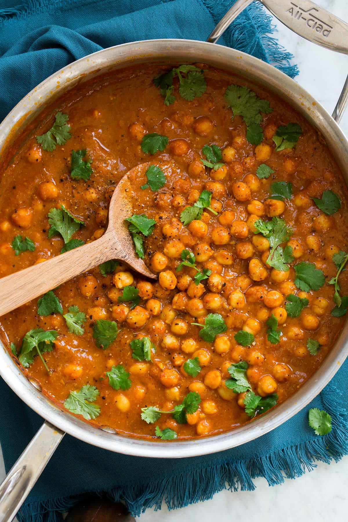 Chickpea Curry Overhead photo of chickpea curry in a stainless steel pan set over a blue cloth.