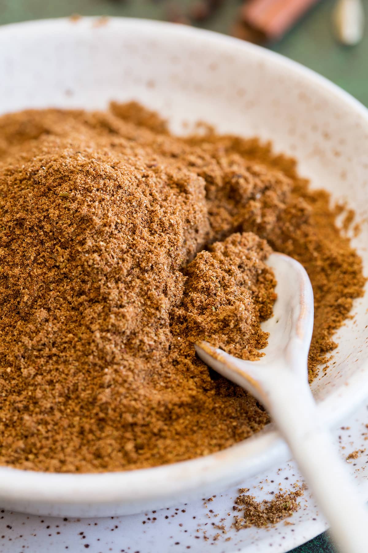 Garam Masala Garam masala spice blend shown up close in a bowl with a small spoon.