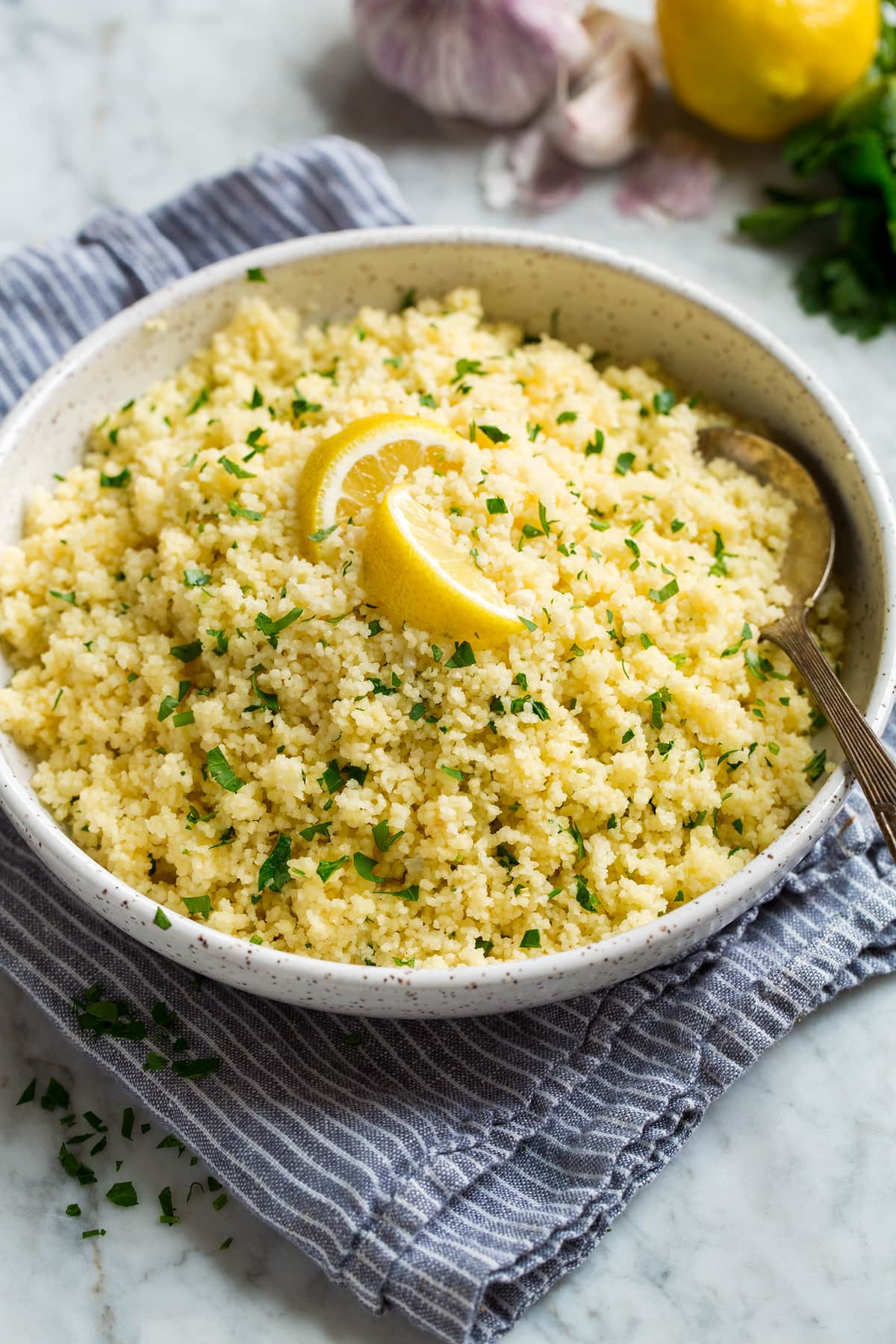 Lemon Couscous Lemon couscous shown in a white bowl over a grey striped cloth.