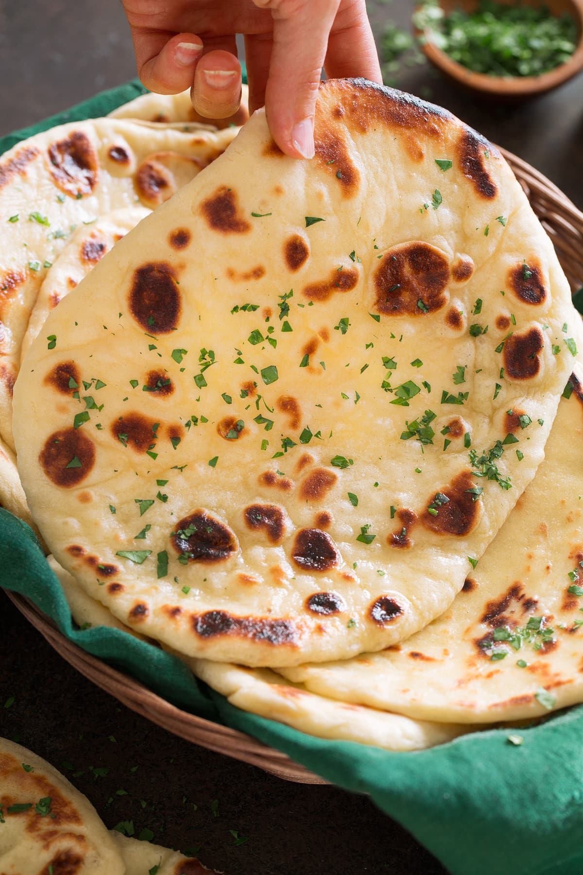 Naan Photo of hand lifting soft naan bread from basket.