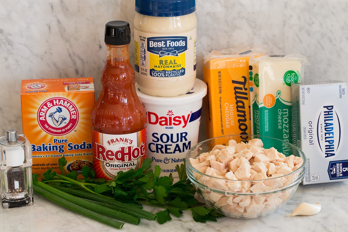 Buffalo Chicken Dip Photos of ingredients for buffalo chicken dip. Includes cooked chicken, buffalo sauce, sour cream, mayonnaise, cheddar cheese, mozzarella cheese, cream cheese, garlic, green onions, parsley, baking soda, salt and pepper.