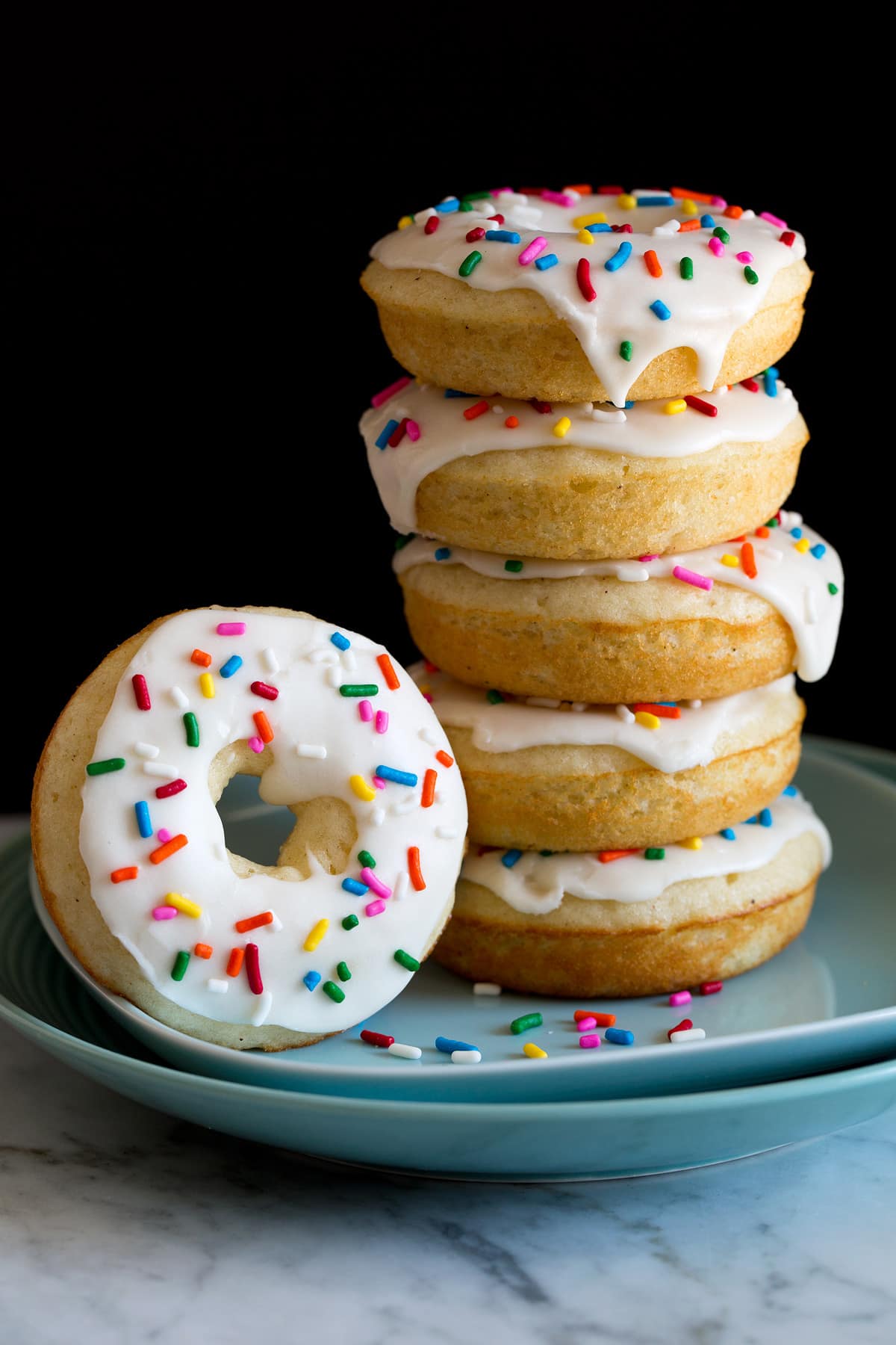 Baked Donuts Image of stack of baked donuts on a plate. They are covered in icing and sprinkles.
