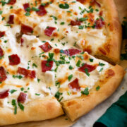 Side angle of sliced chicken alfredo pizza.