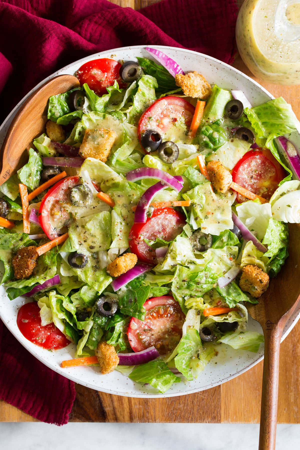 Homemade Italian Dressing Photo: Green iceberg and romaine salad with carrots, olives and tomatoes that has been topped with Italian salad dressing.