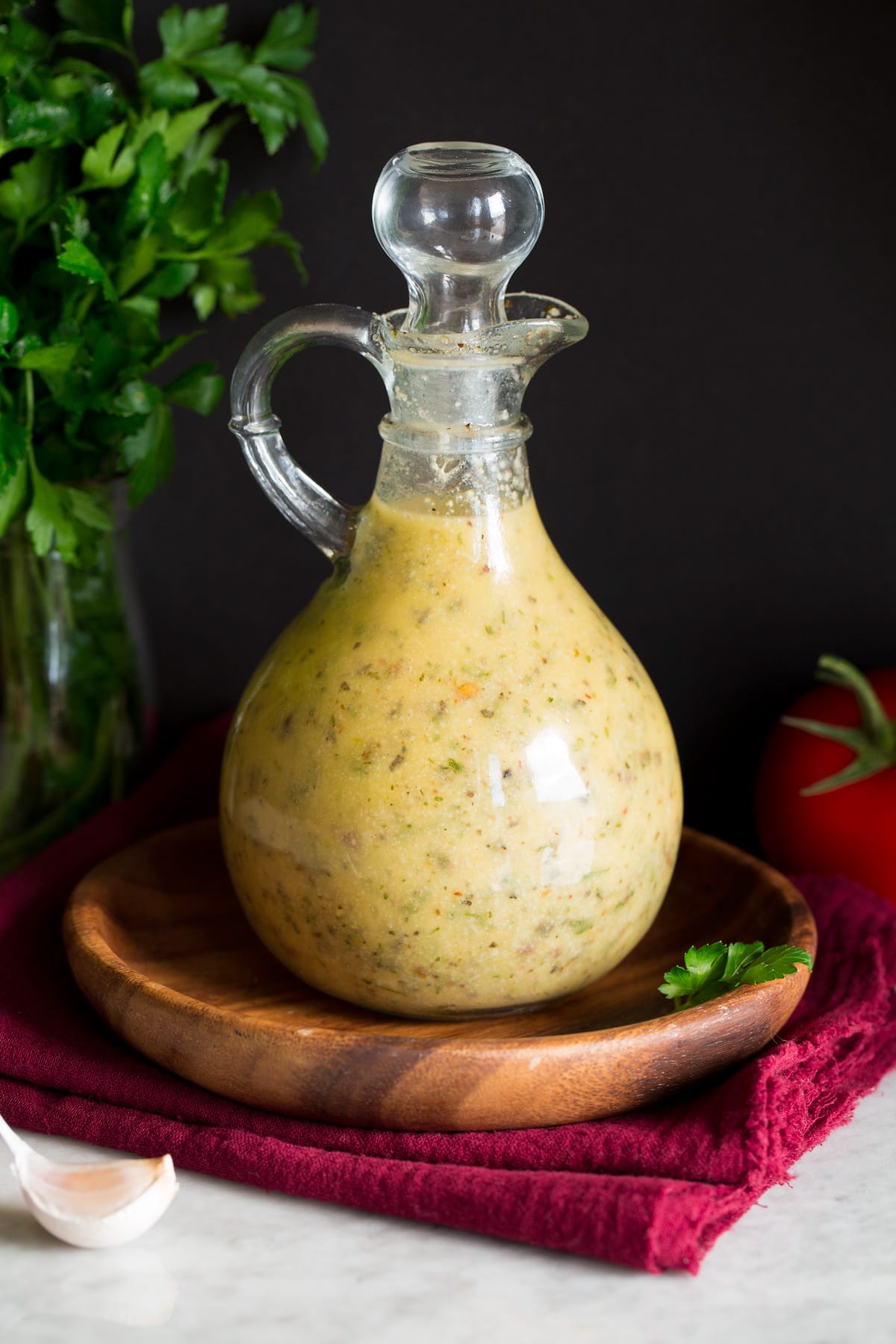 Homemade Italian Dressing Photo: Italian Dressing in a glass bottle set over a wooden plate and a red cloth.