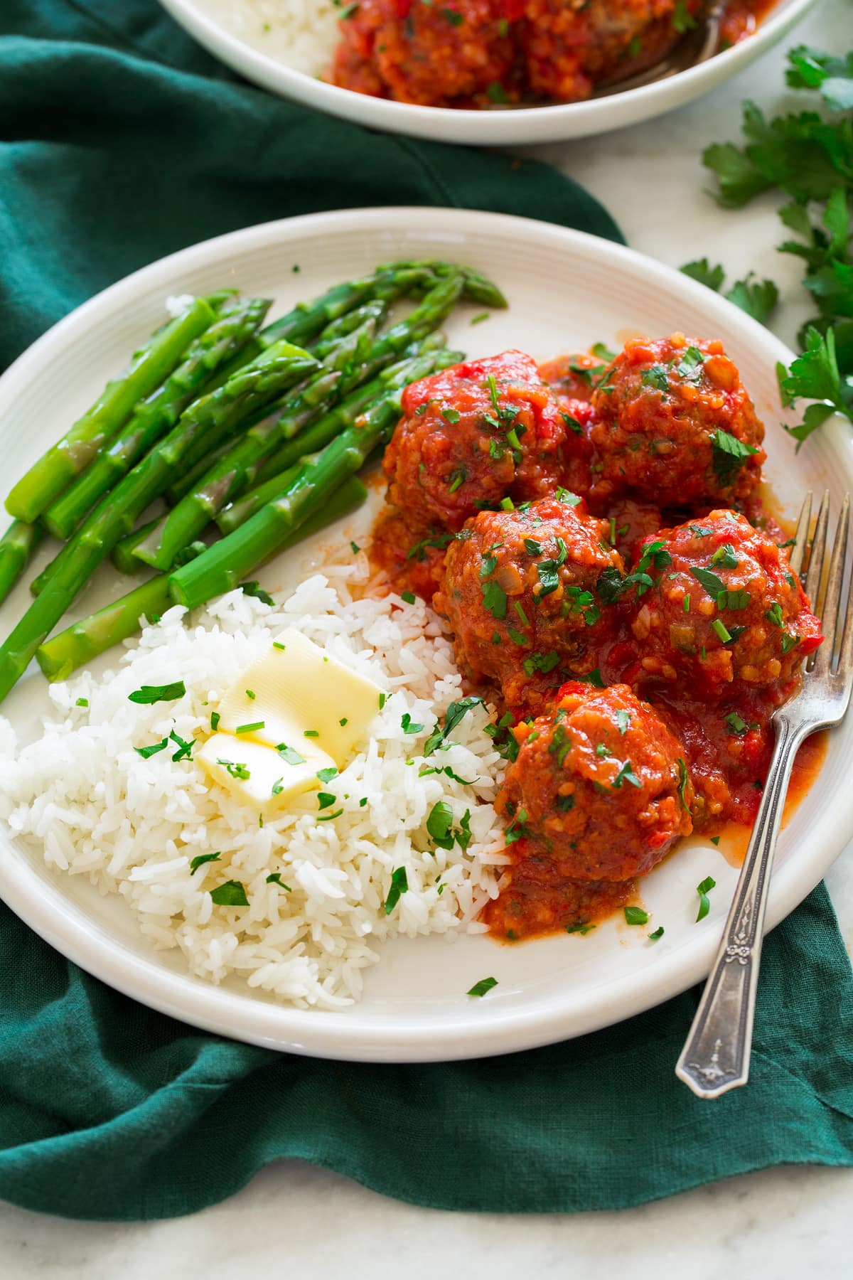 Porcupine Meatballs Porcupine Meatballs shown on a large white plate with sides of rice and butter and steamed asparagus.