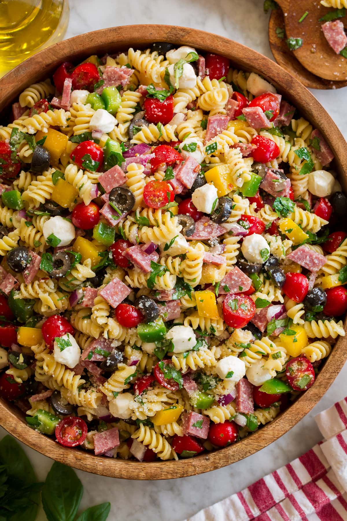 Italian Pasta Salad Photo: Italian Pasta Salad shown in a large wooden bowl from above. Bowl is resting on a marble surface with a striped cloth and jar of olive oil to the side.