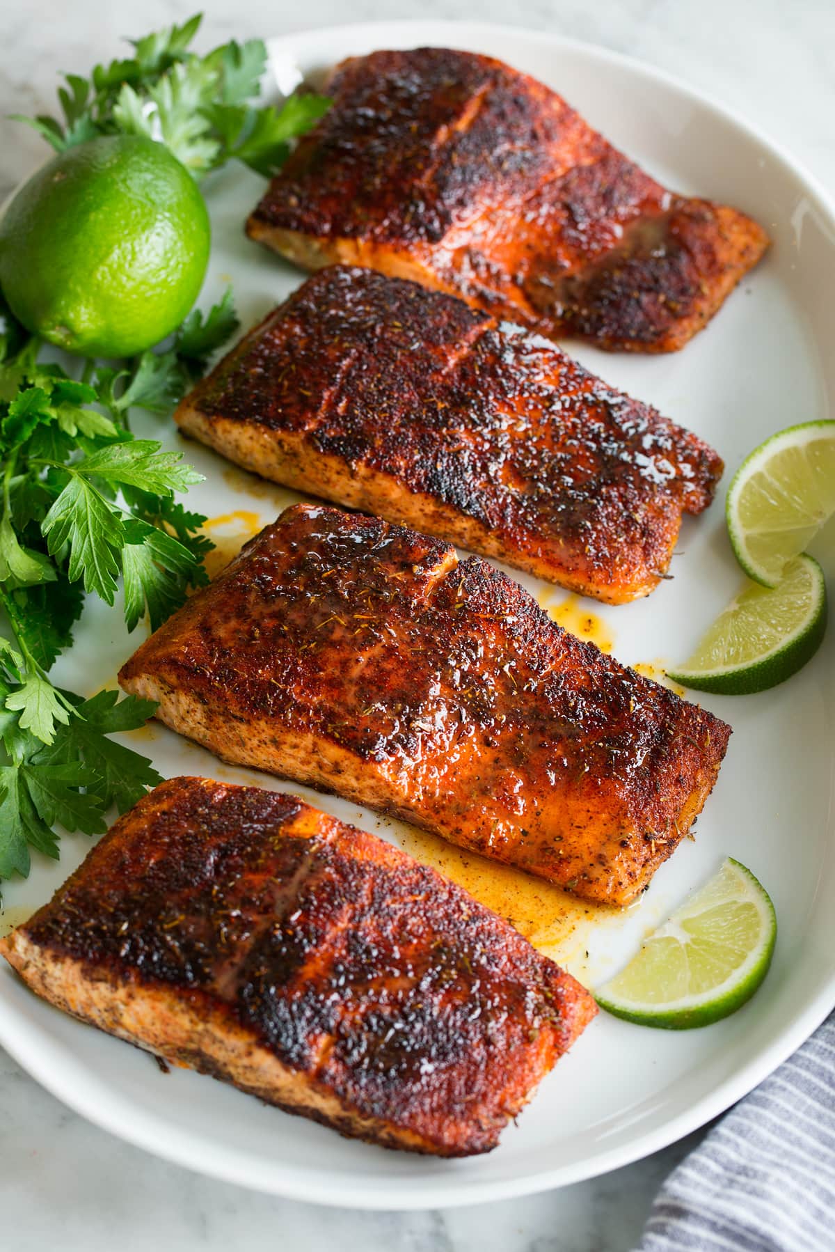 Blackened Salmon Photo: Blackened salmon shown topped with buttery honey lime sauce. Parsley and limes are shown as garnishes.