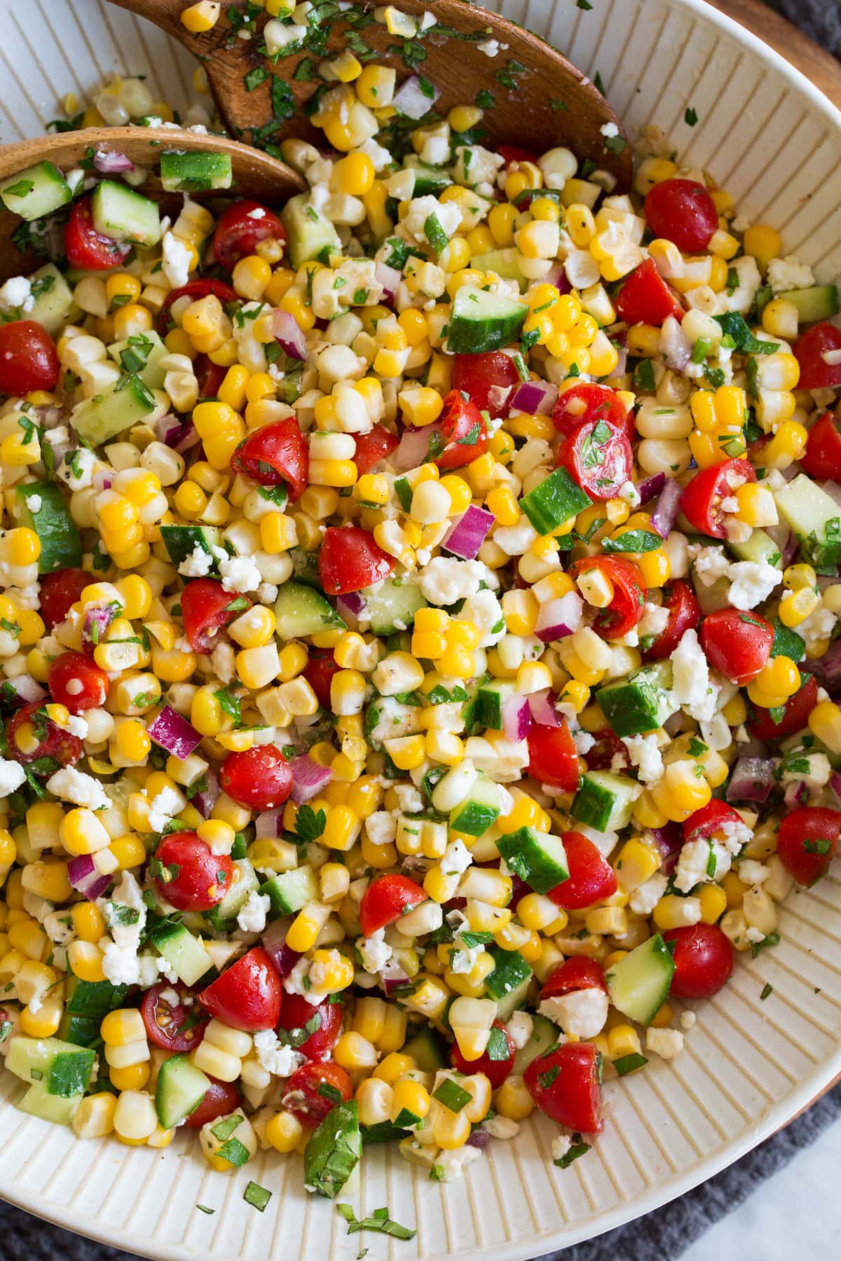 Corn Salad Photo: Corn salad shown close up from above in a serving bowl with wooden serving spoons.