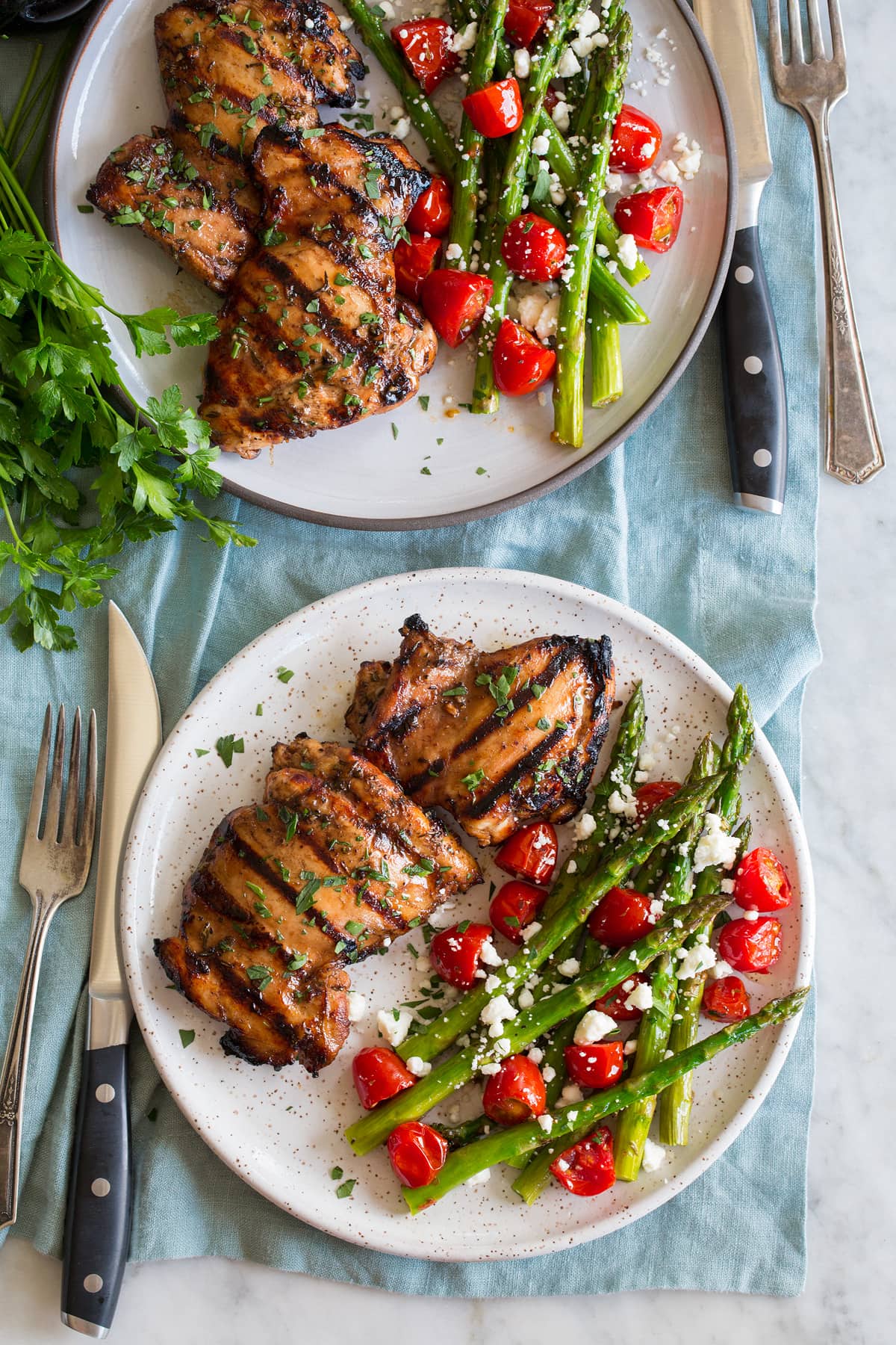 Balsamic Chicken Photo: Two servings of balsamic chicken shown on serving plates with a serving suggestion of roasted asparagus and tomatoes.