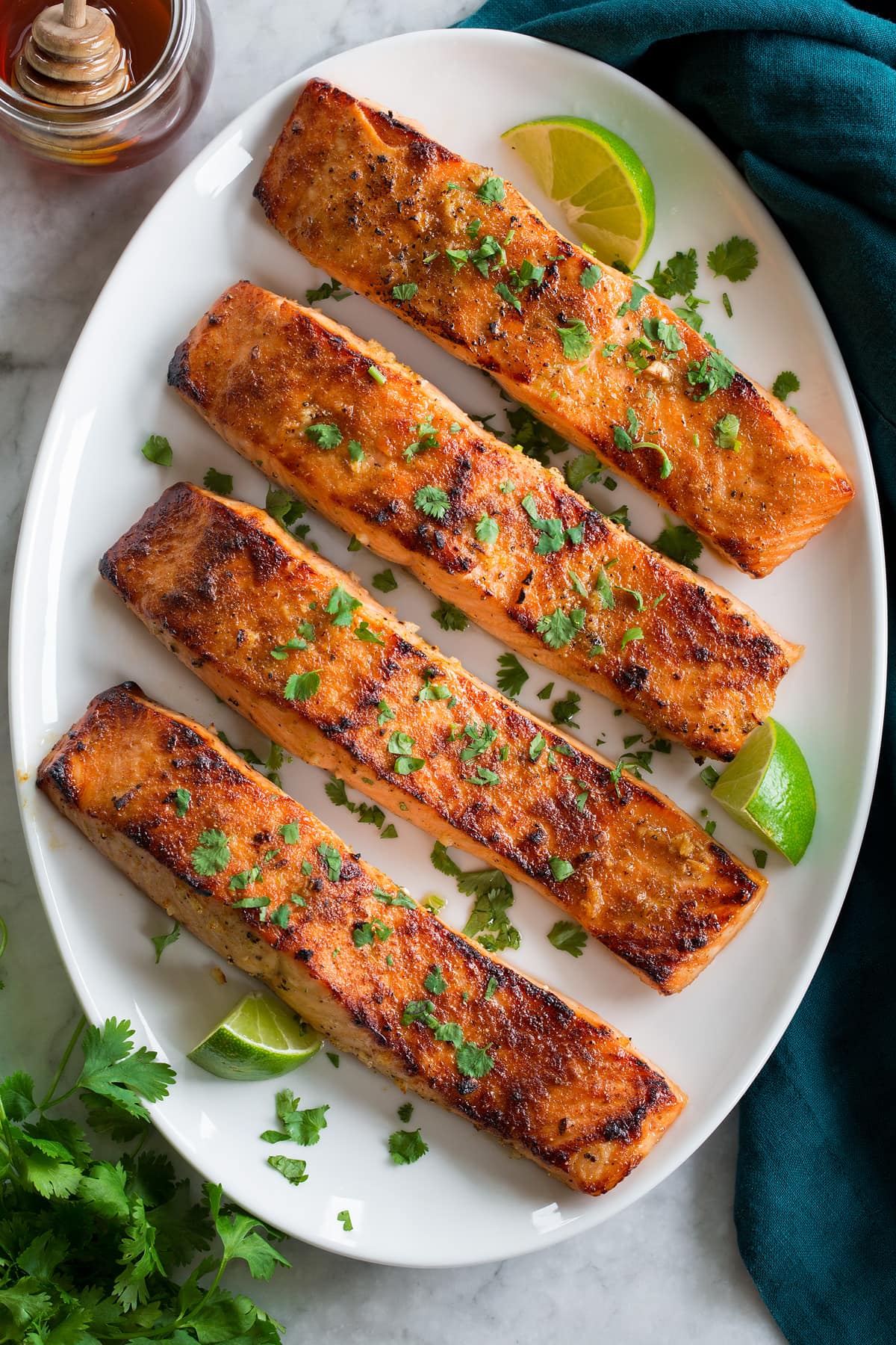 Broiled Salmon Row of broiled salmon shown from overhead on an a white oval serving platter on a marble surface.