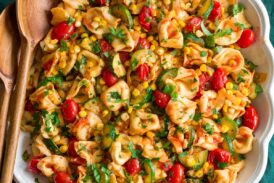 Photo: Tortellini shown in an oval platter from overhead. Platter is on a green cloth on a marble surface.