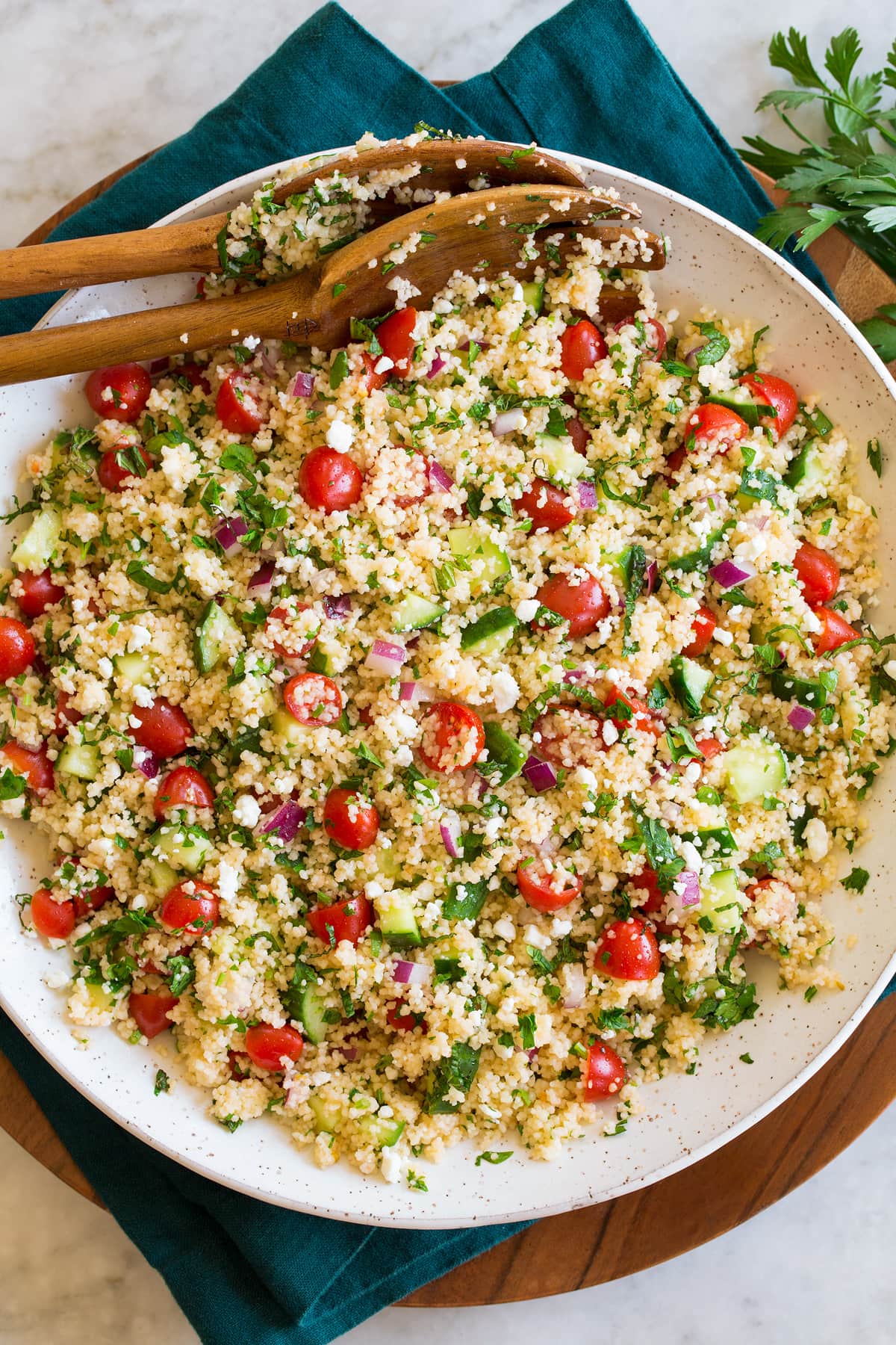 Couscous Salad Couscous Salad shown form above in a white ceramic bowl resting on a blue cloth and wooden plate.