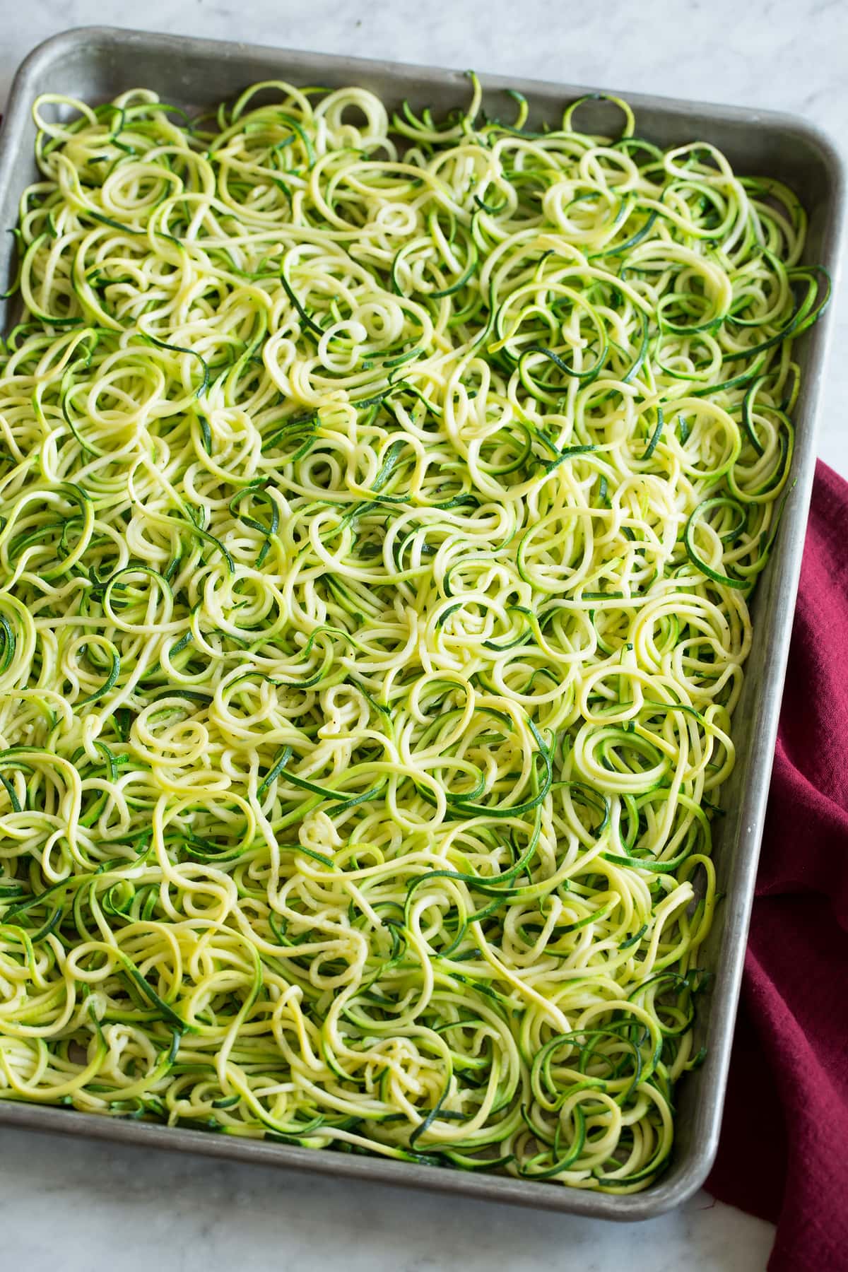 Zucchini Noodles - Zoodles Roasted zoodles shown on a baking sheet from a side angle.
