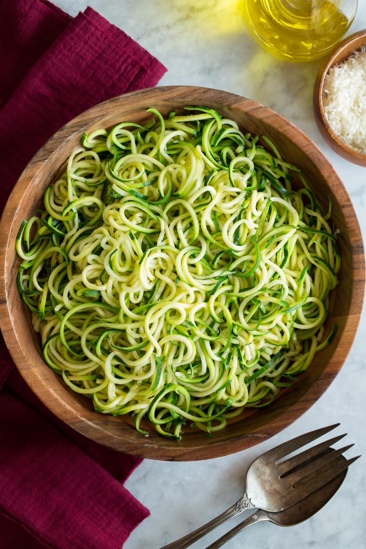 Zucchini Noodles - Zoodles Plain cooked zucchini noodles shown in a wooden bowl on a white marble surface.