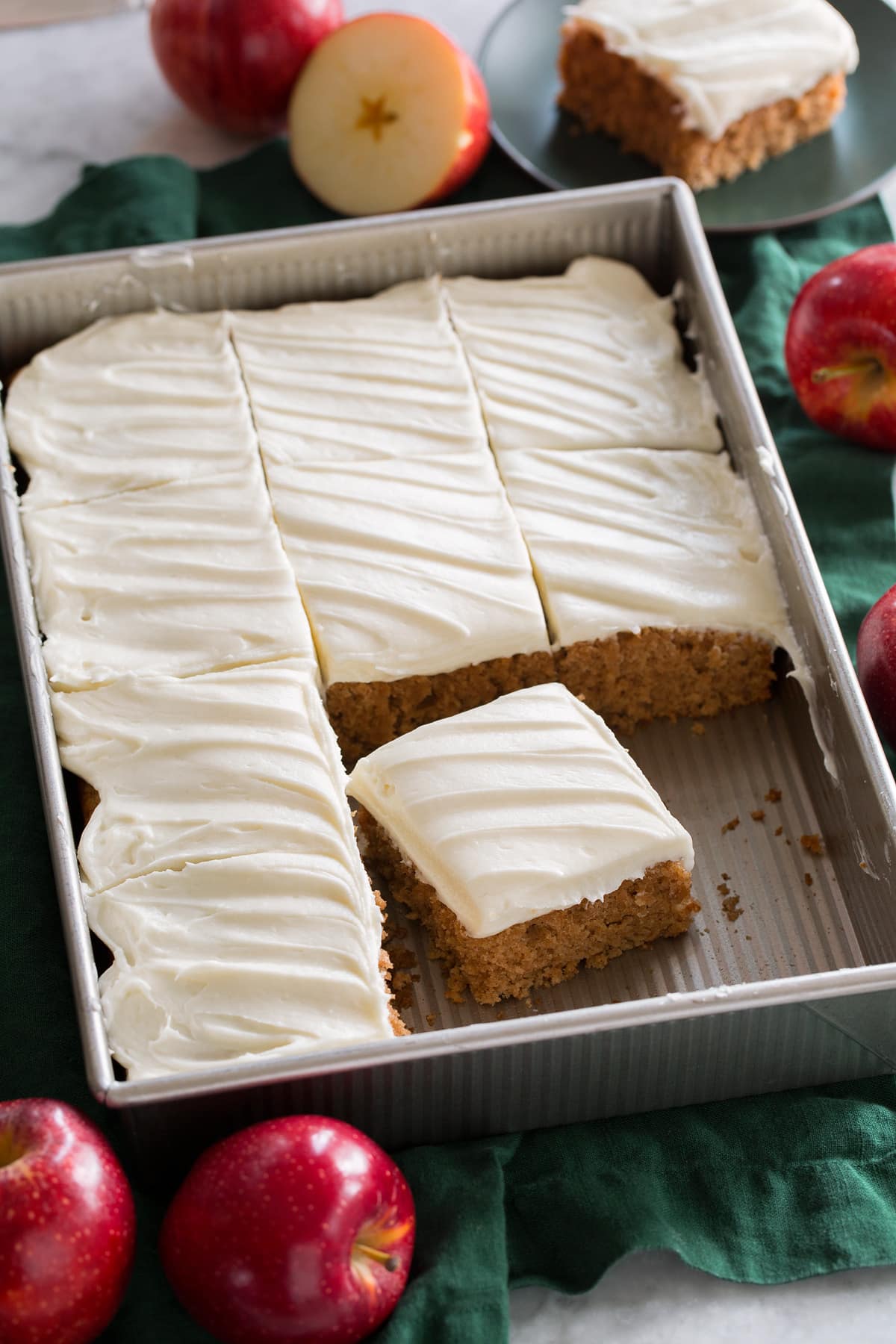 Applesauce Cake Applesauce cake topped with cream cheese frosting shown in a metal baking sheet over a green cloth.