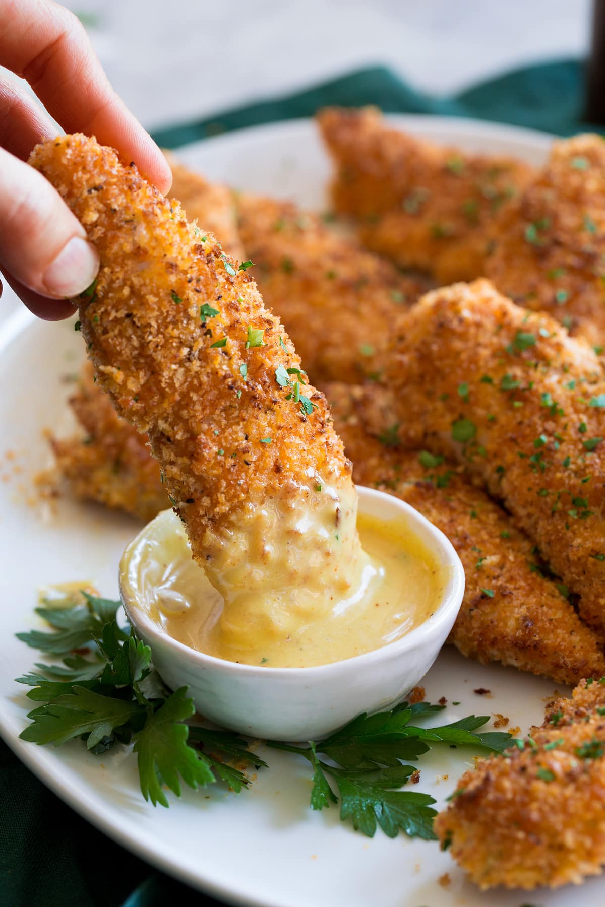 Baked Chicken Tenders Chicken tender being dipped into honey mustard sauce.
