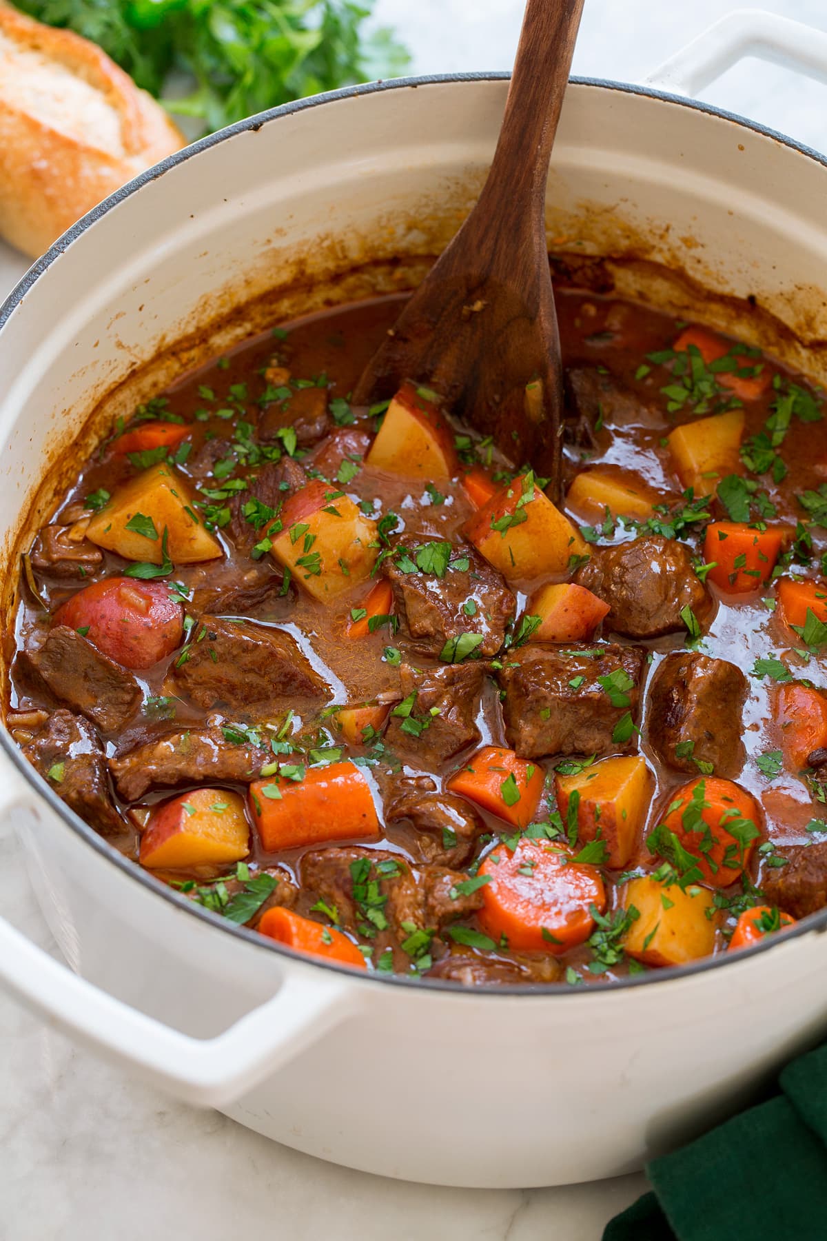 Beef Stew Beef stew with potatoes, carrots and chuck roast in a pot with a wooden spoon, it is shown from the side.