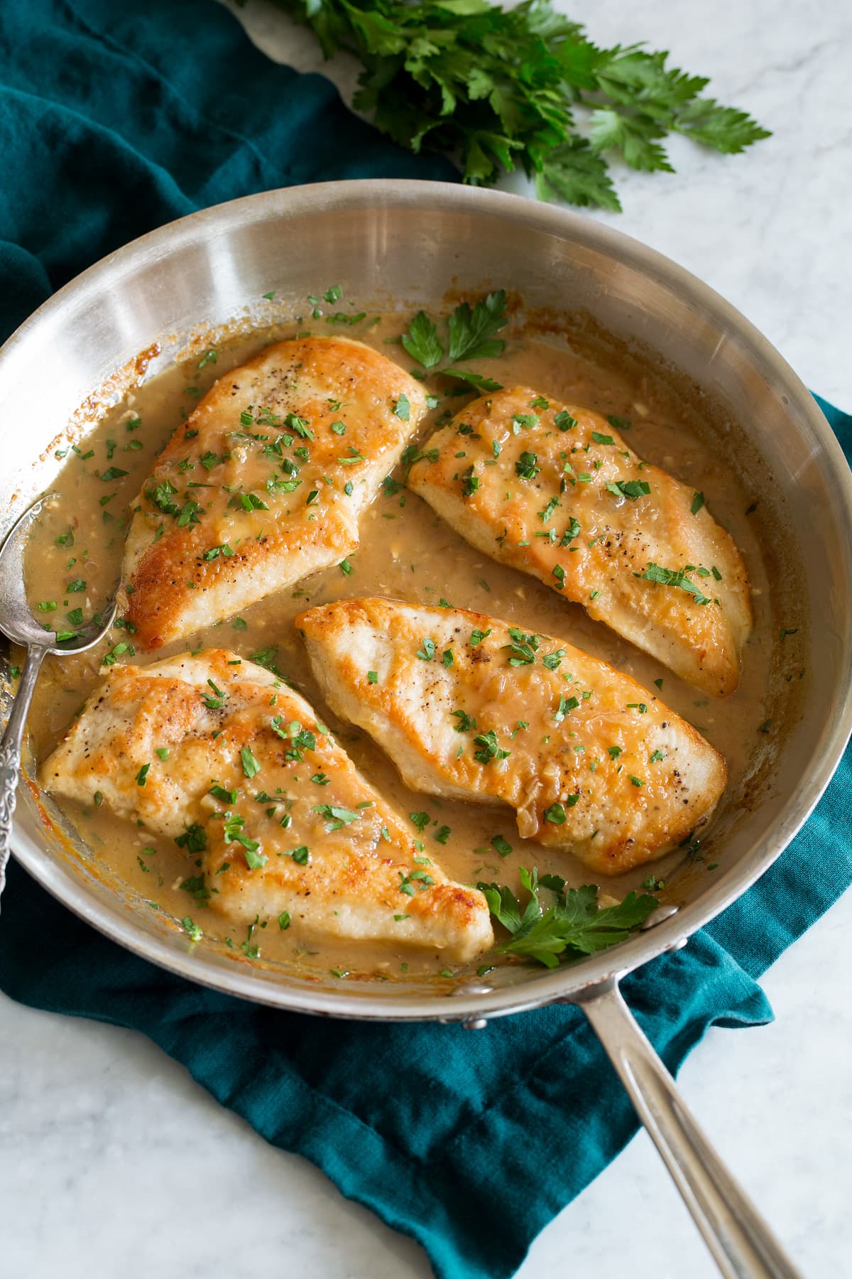 Chicken in White Wine Sauce Chicken breasts in white wine and onion sauce in a skillet.