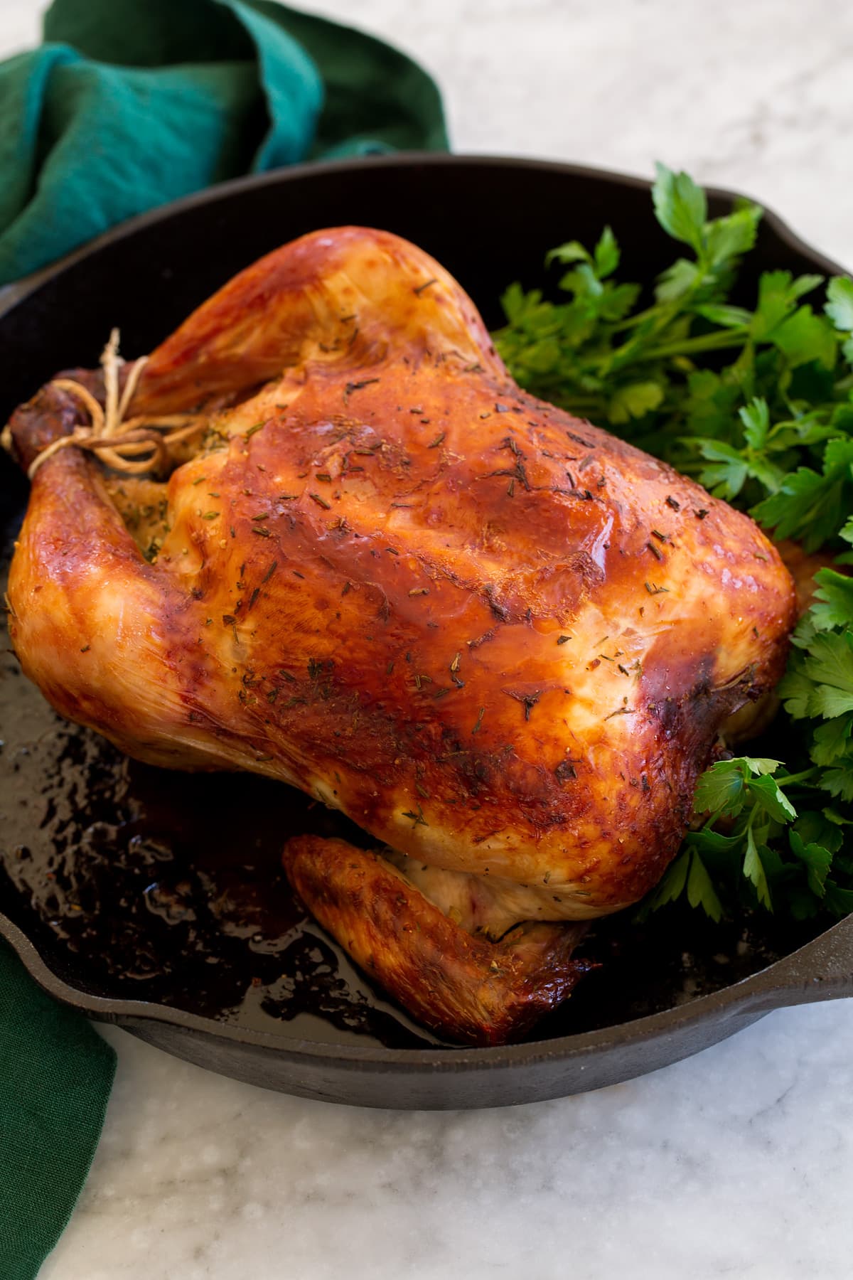 Buttermilk Roast Chicken Whole roasted chicken shown in a cast iron skillet with fresh herbs.