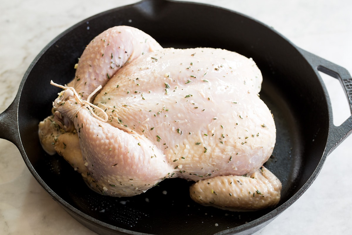 Buttermilk Roast Chicken Raw chicken that's legs are trussed in a cast iron skillet before roasting.