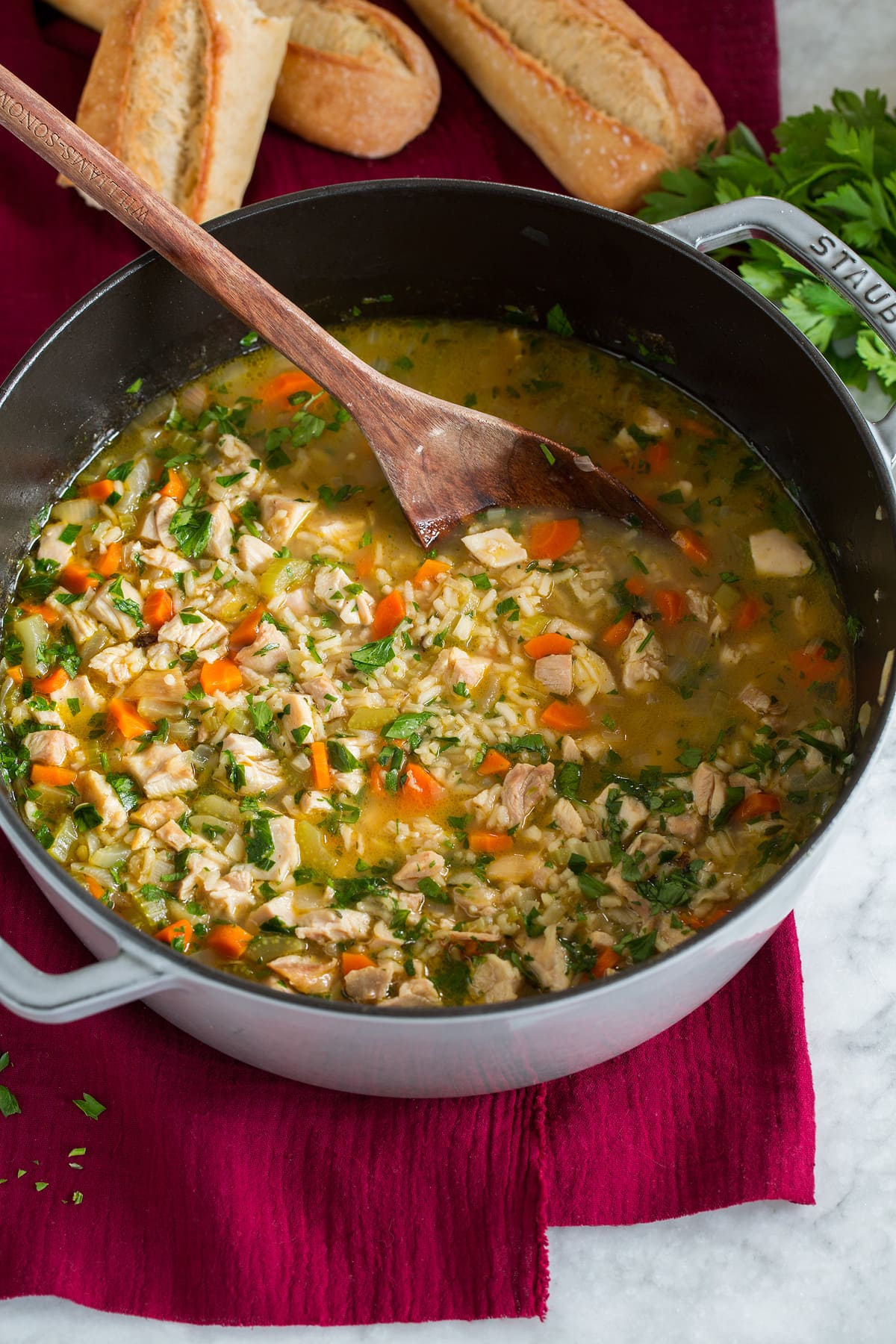 Chicken and Rice Soup Pot of chicken and rice soup with a wooden ladle. Baguette bread is shown in the background.
