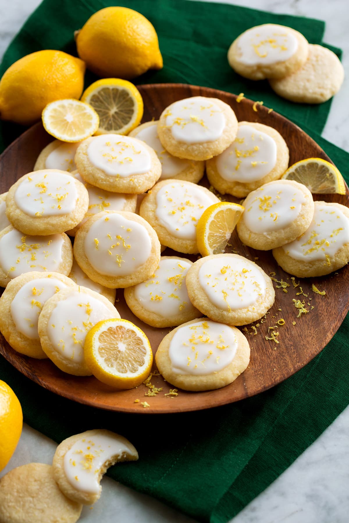 Lemon Meltaway Cookies Lemon meltaway cookies shown on a wooden plate over a green cloth on a marble surface with lemons for decoration.