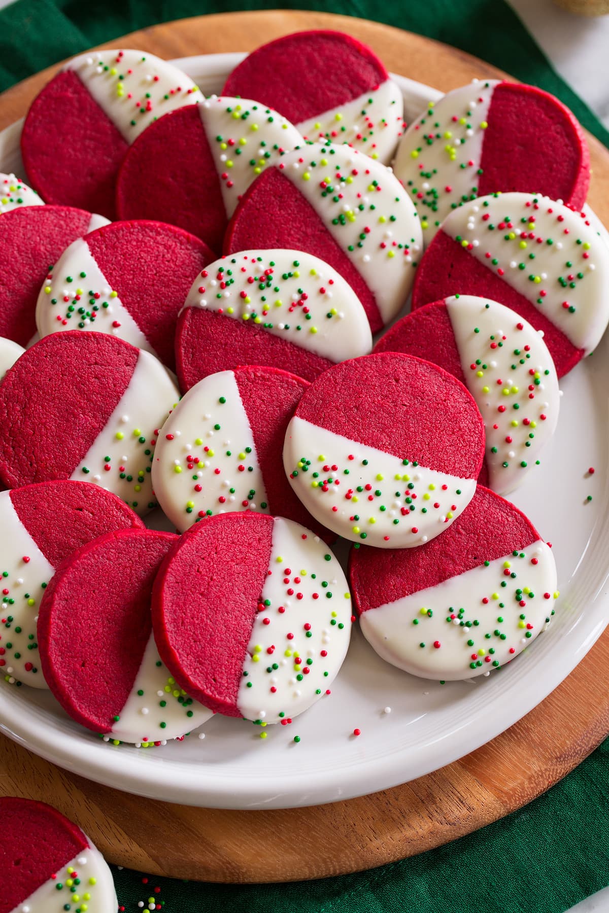 Red velvet shortbread cookies shaped in rounds, dipped in white chocolate and decorated with sprinkles.