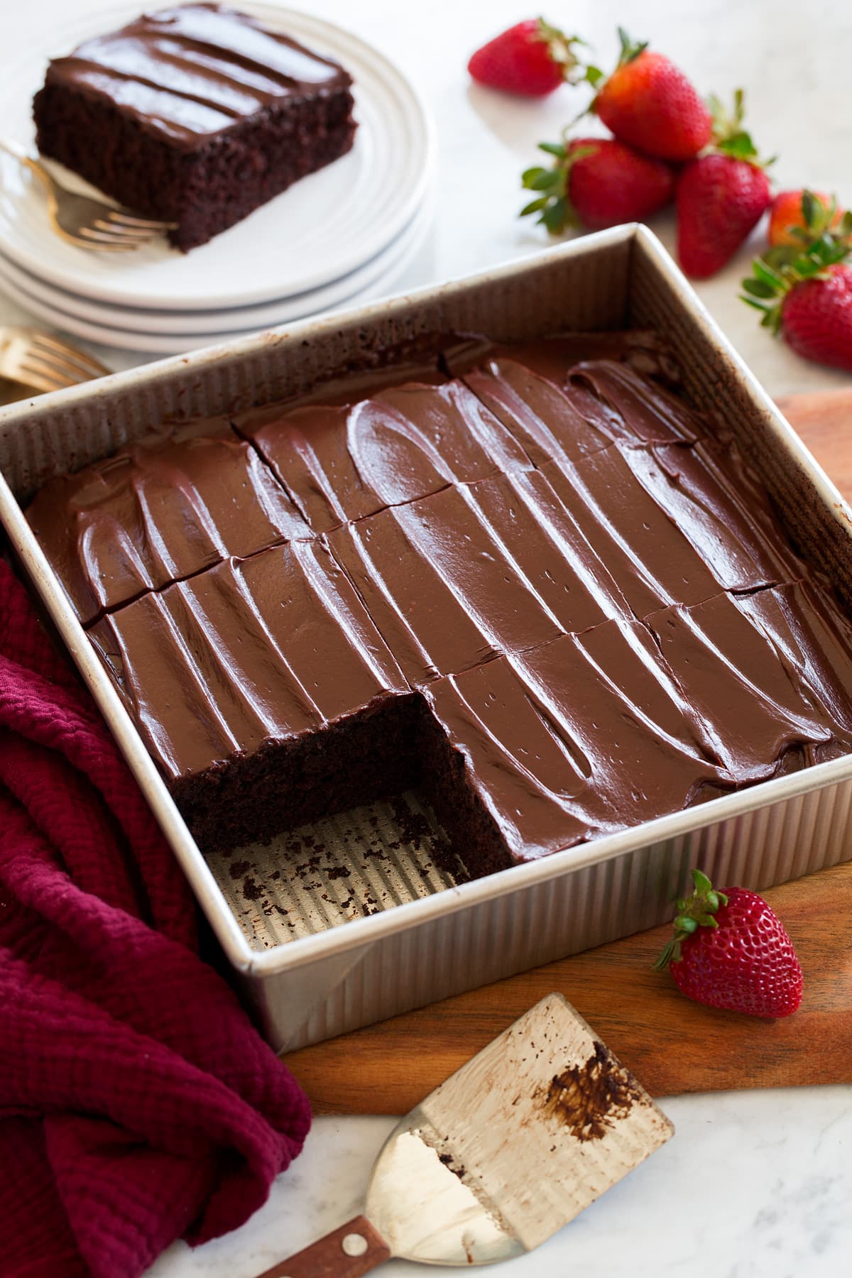 Chocolate Cake Sheet pan style chocolate cake shown in a metal 9 by 9-inch baking dish cut into squares and topped with optional icing.
