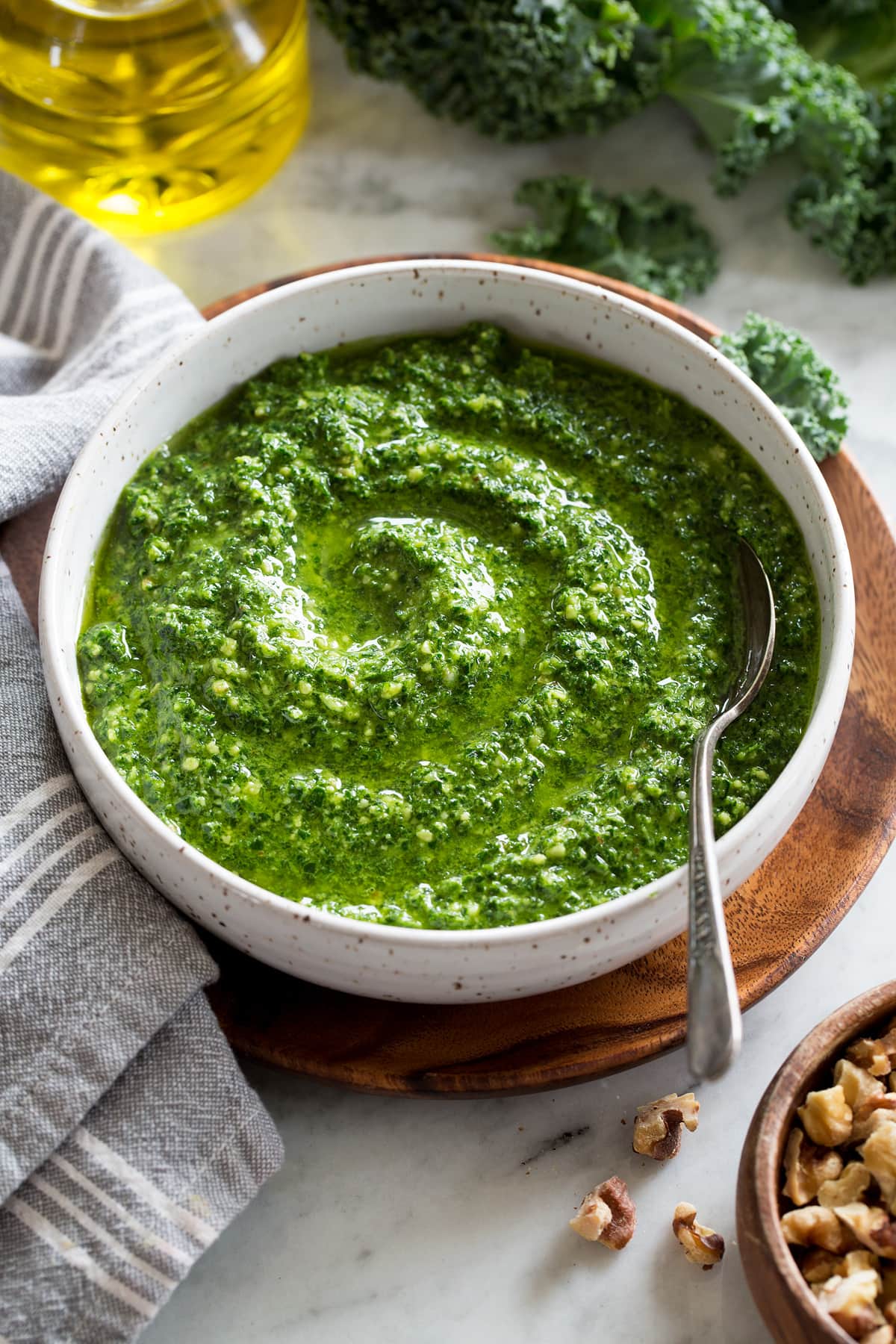 Kale Pesto Kale pesto in a white bowl over a wooden plate.