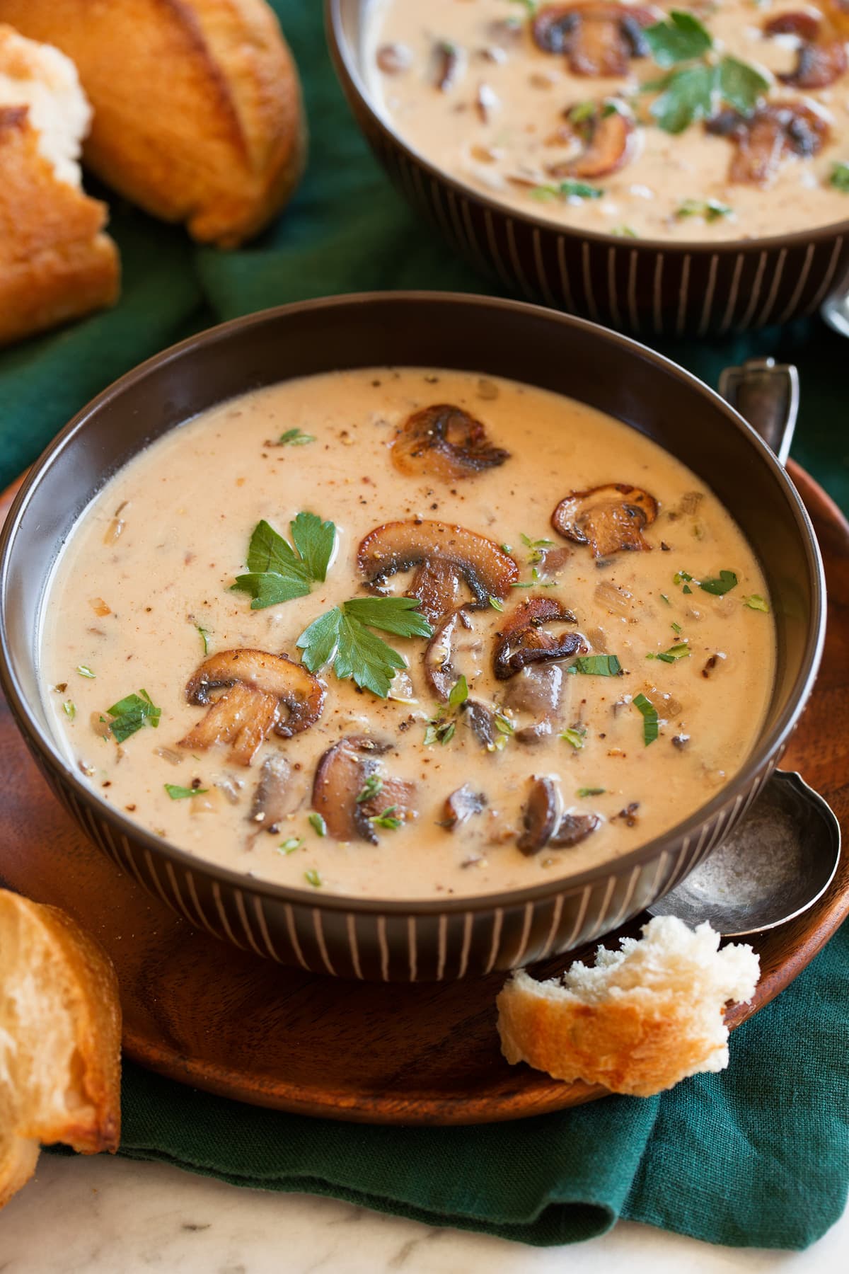 Cream of Mushroom Soup Single serving of cream of mushroom soup in a brown bowl garnished with sauteed mushrooms.