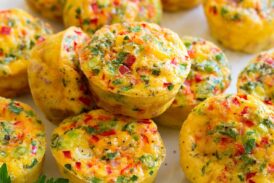 Egg muffins shown on a white serving platter over a wooden platter and a blue cloth.