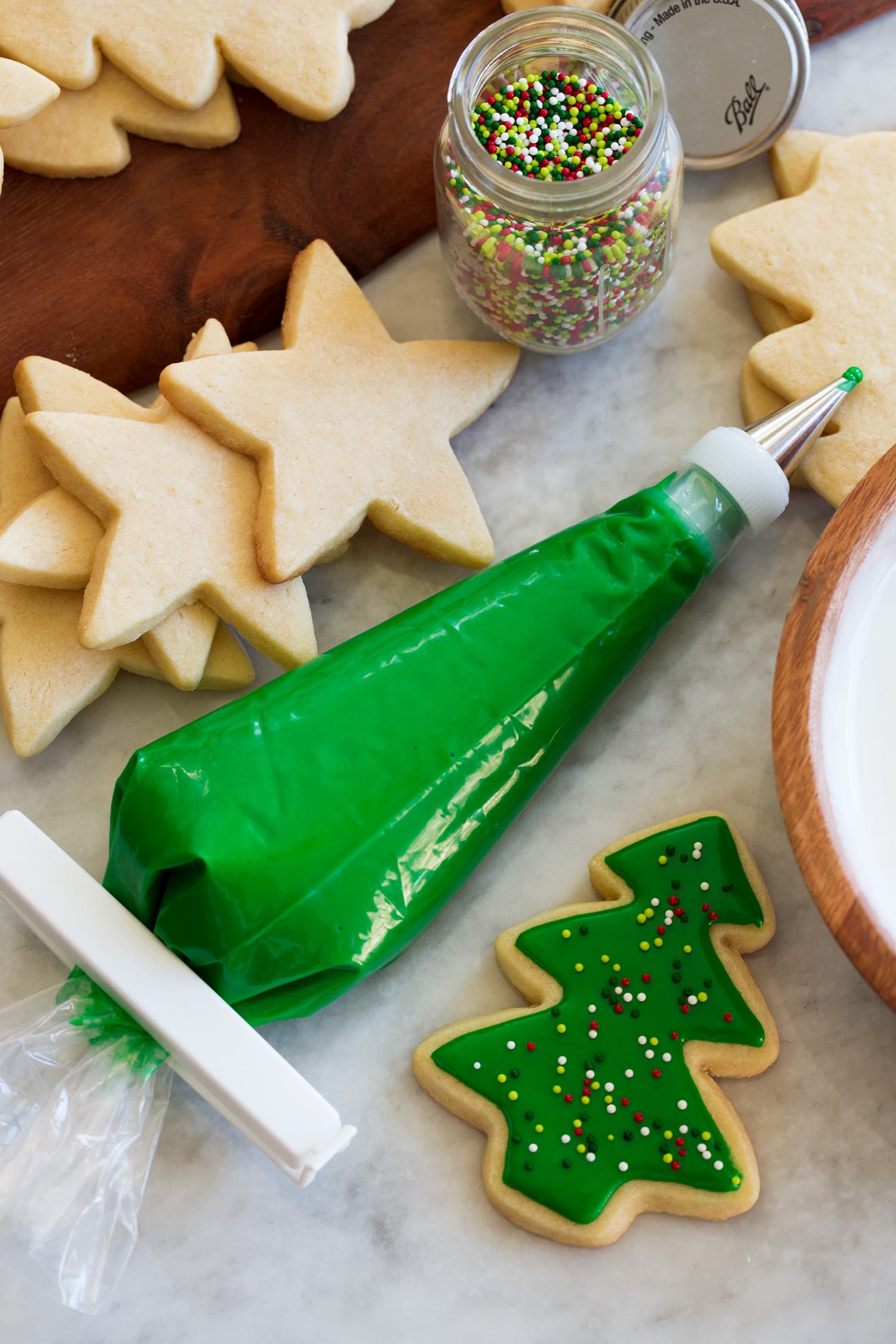 Sugar Cookie Icing Sugar cookie icing in a piping bag. Icing is tinted a green color and there is a cut out cookie next to it showing how to decorate with icing and sprinkles.