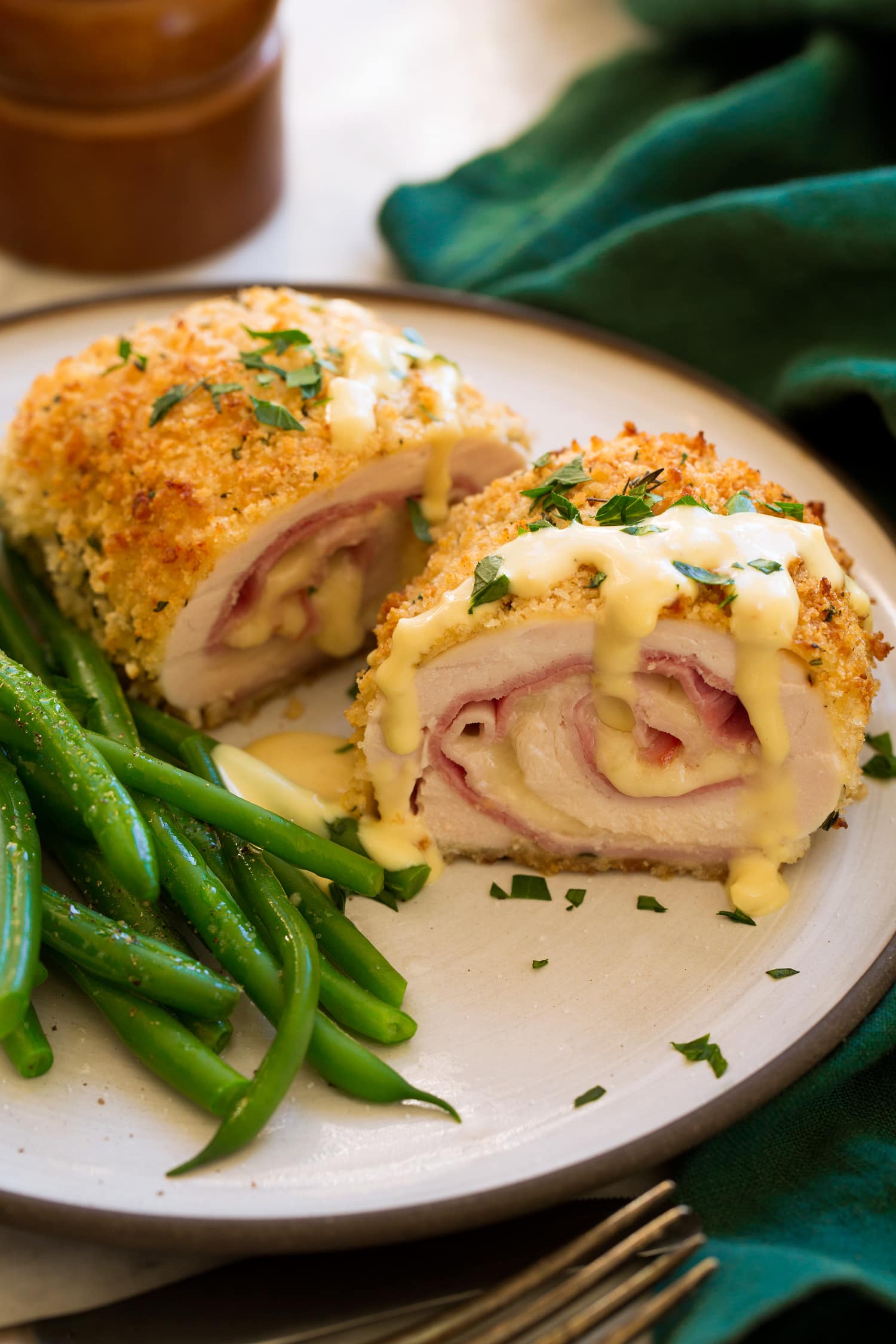 Chicken Cordon Bleu Chicken Cordon Bleu shown sliced in half with sauce on top. Green beans shown to the side.