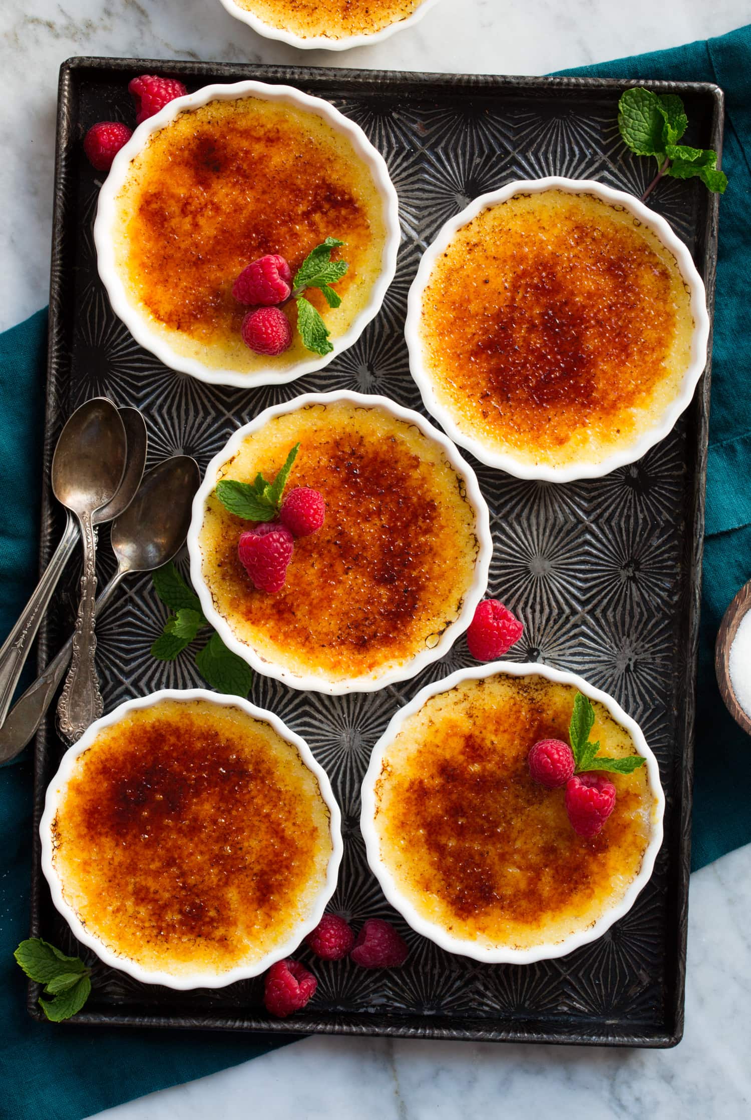 Creme Brûlée Overhead photo of five completed creme brûlée on a dark tray.