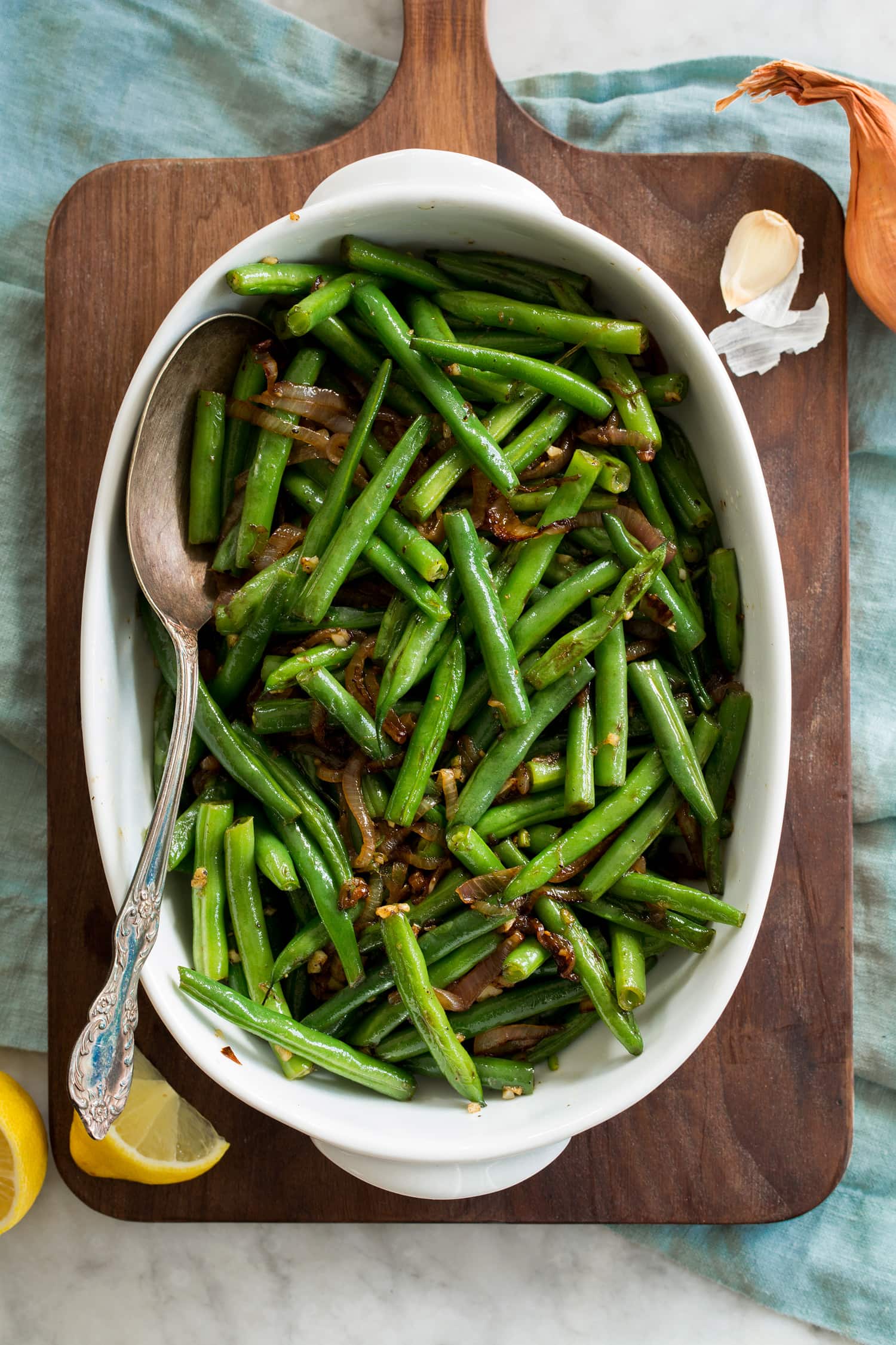 Sauteed Green Beans Sauteed green beans shown from above in an oval ceramic dish on a wooden tray.