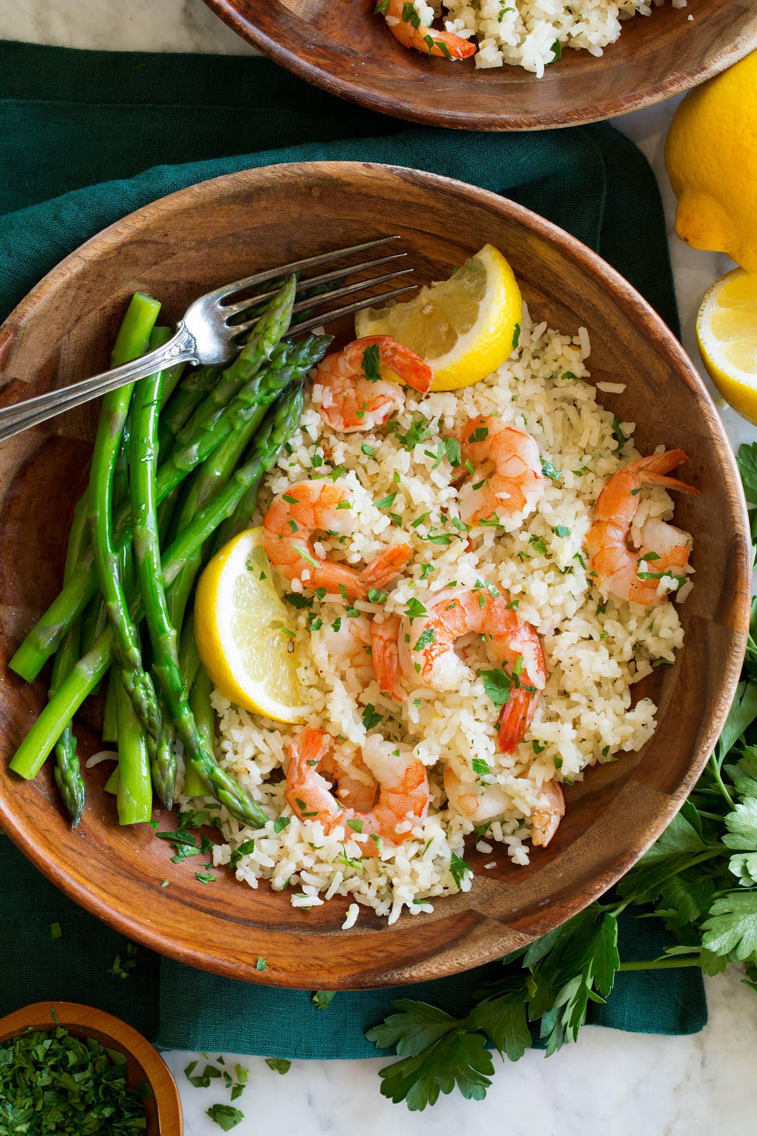 One Pot Shrimp and Rice Rice, shrimp and asparagus in a wooden bowl with lemon slices.