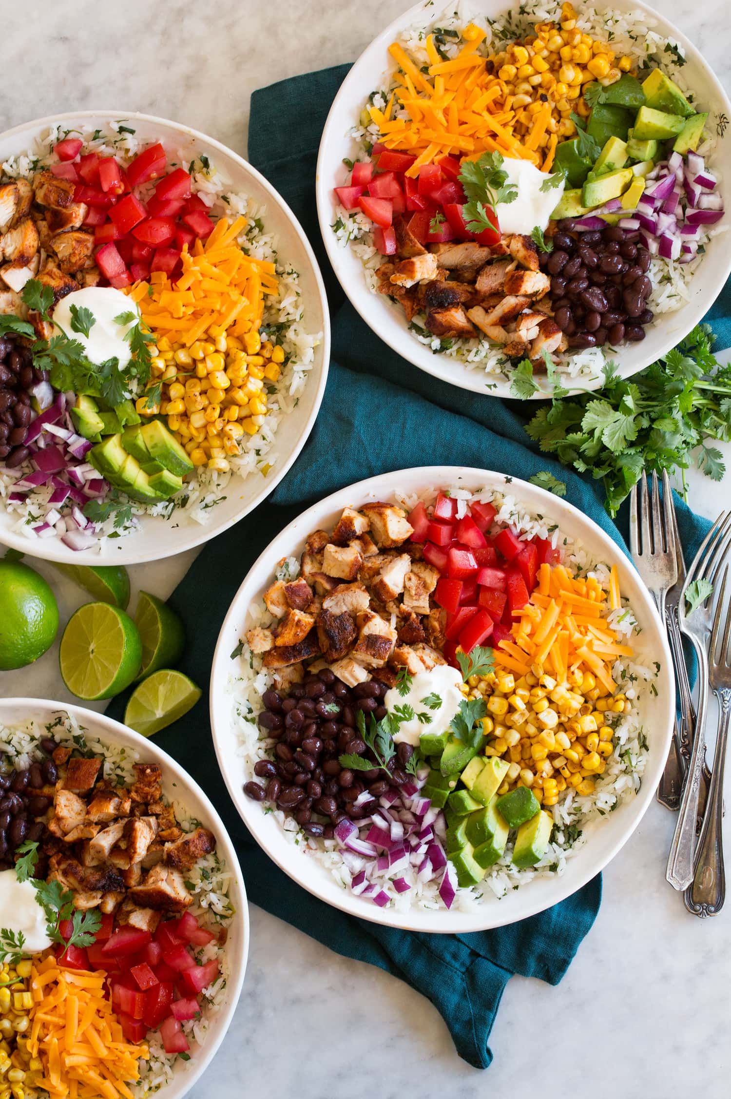 Four burrito bowl servings with corn, tomatoes, cheddar, avocado, black beans, red onion, sour cream and chopped chicken thighs. Four burrito bowl servings with corn, tomatoes, cheddar, avocado, black beans, red onion, sour cream and chopped chicken thighs.