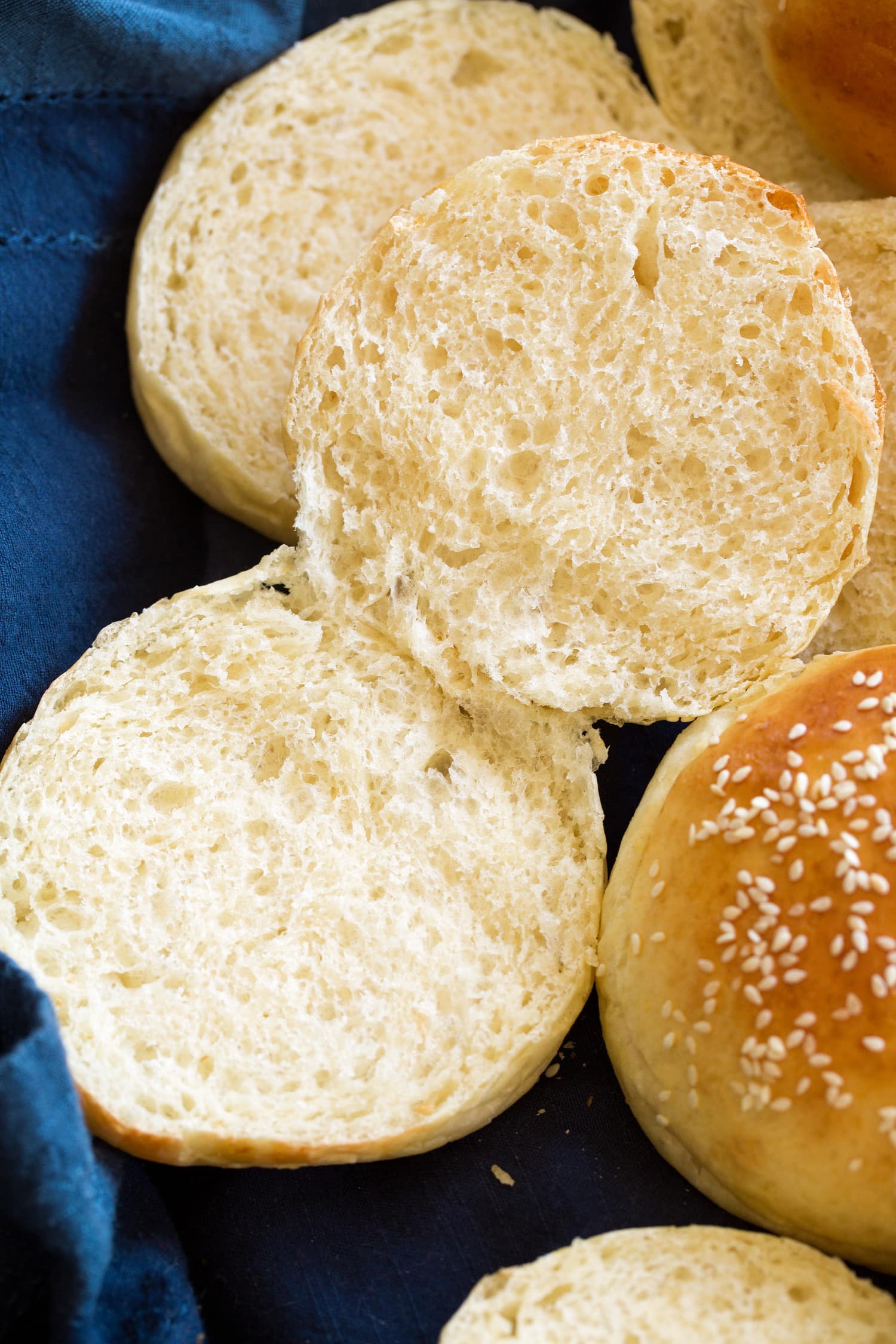 Homemade Hamburger Buns Close up photo showing texture of homemade hamburger bun sliced in half with soft airy crumb.